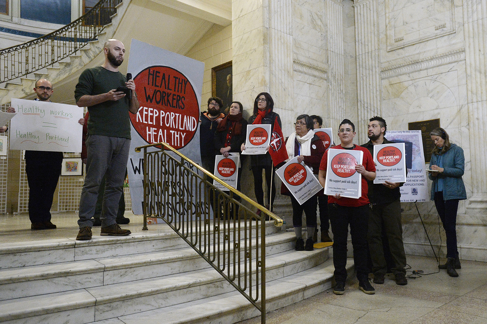 Rally attendees holding signs with messages in favor of paid sick leave