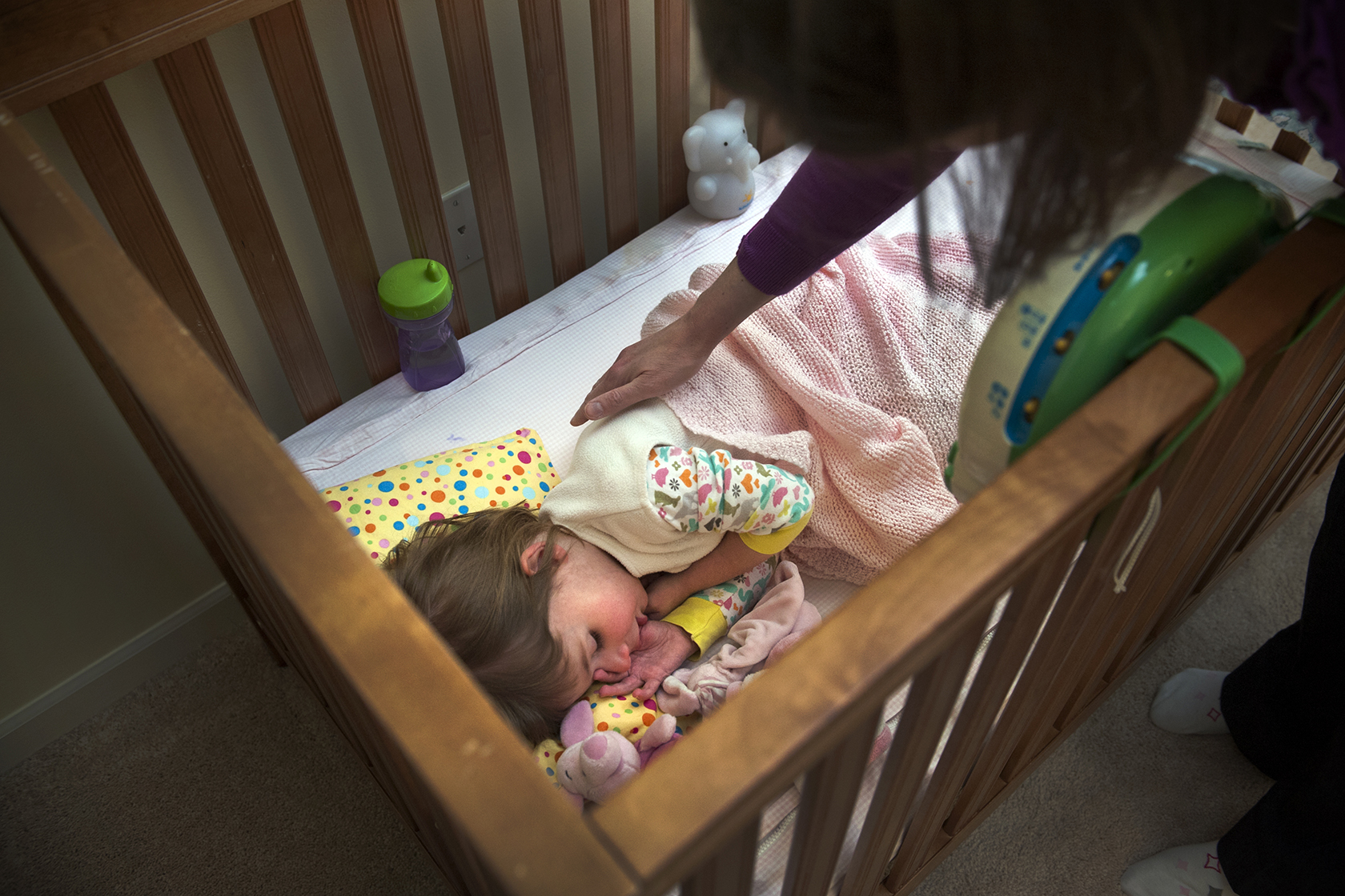 Woman looking down on daughter in crib