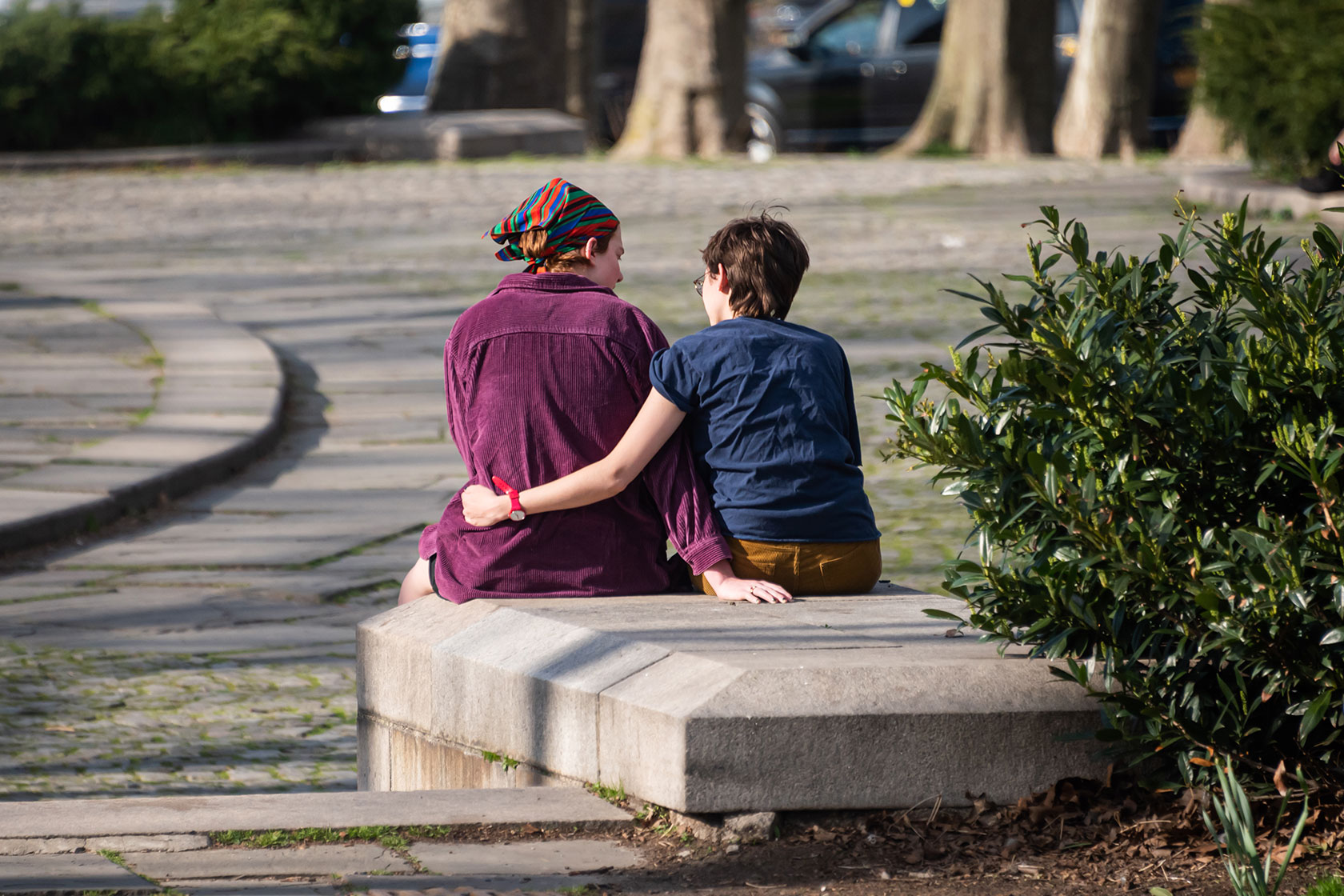 Photo shows a couple sitting together on a park bench.