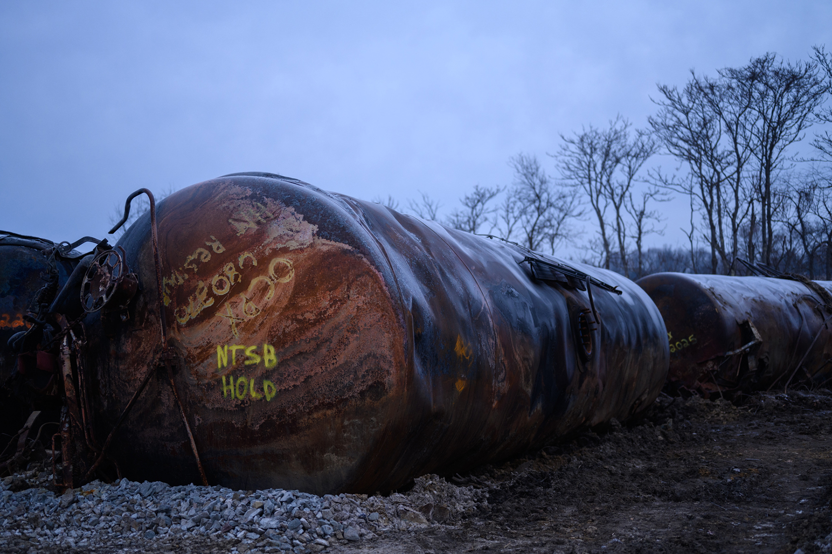 Damaged tanks after train derailment with trees in background