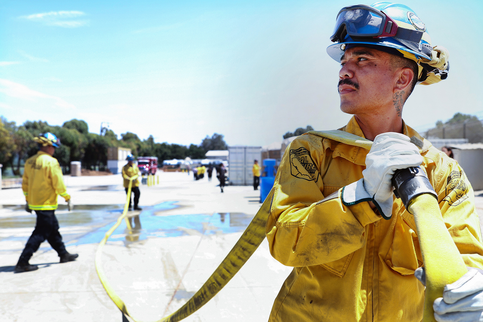 Person in uniform in foreground holding fire hose