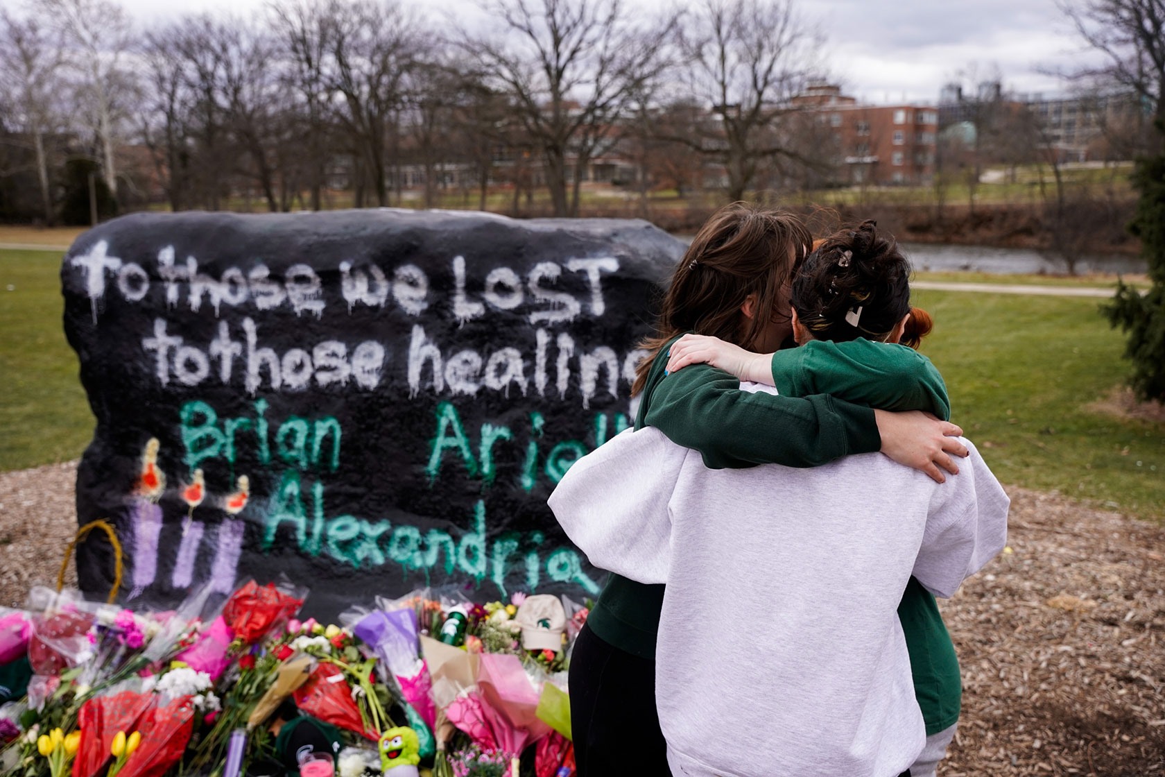 Students hug each other after placing flowers honoring the lives of those killed during the Michigan State shooting.