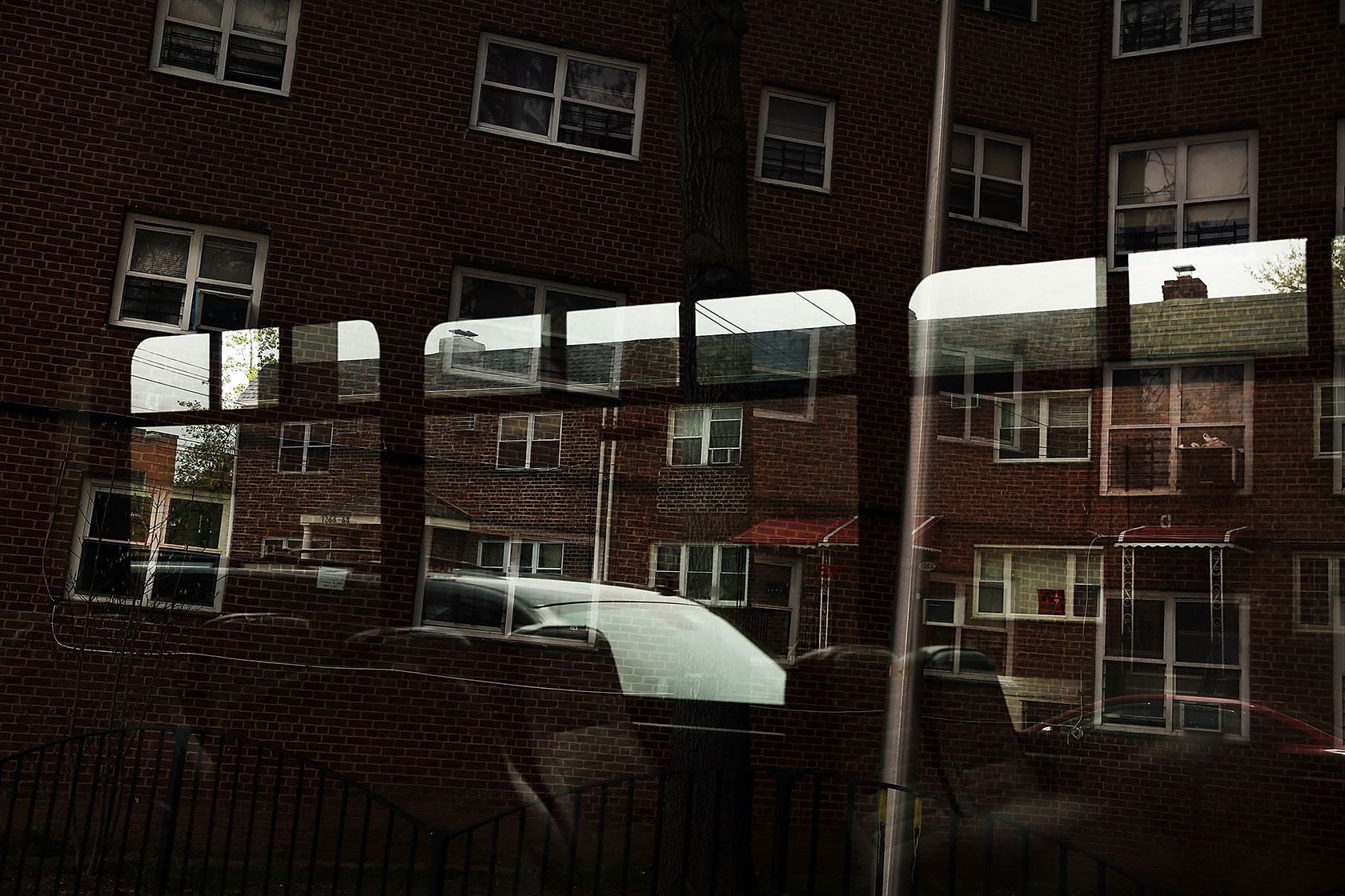 A housing complex in the Bronx is reflected in a window.