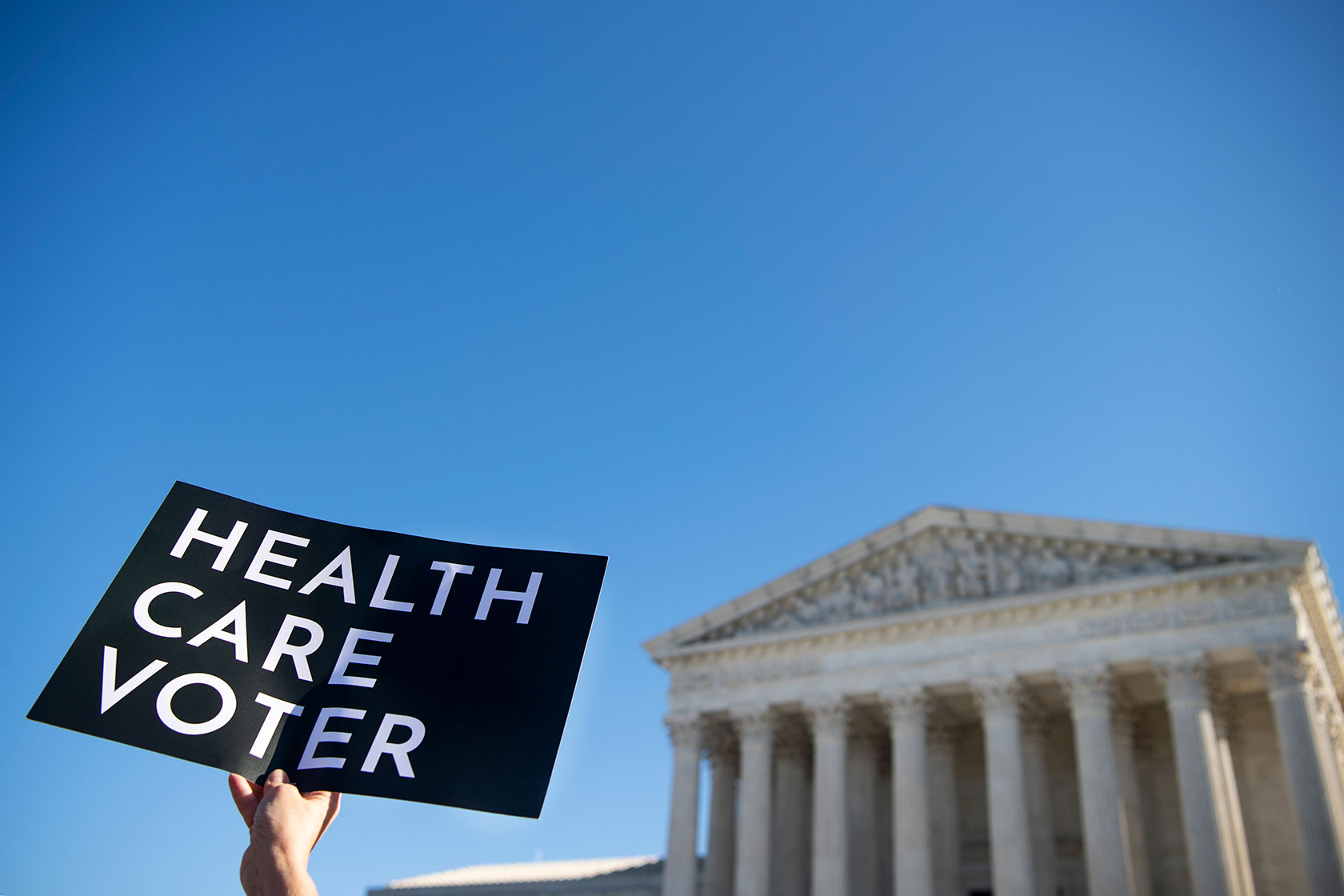 A demonstrator holds up a sign in support of the Affordable Care Act in front of the Supreme Court.