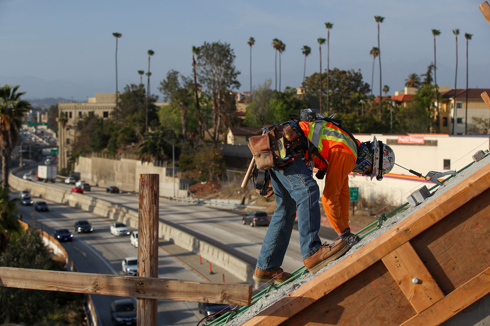 A view of the 101 Freeway below, a construction worker works on a bridge that crosses the 101 Freeway and Los Angeles River in Los Angeles