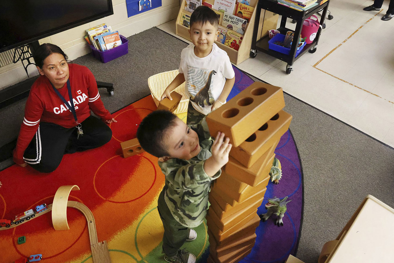Students at a preschool in Chicago play with blocks as an instructor looks on, January 2023.