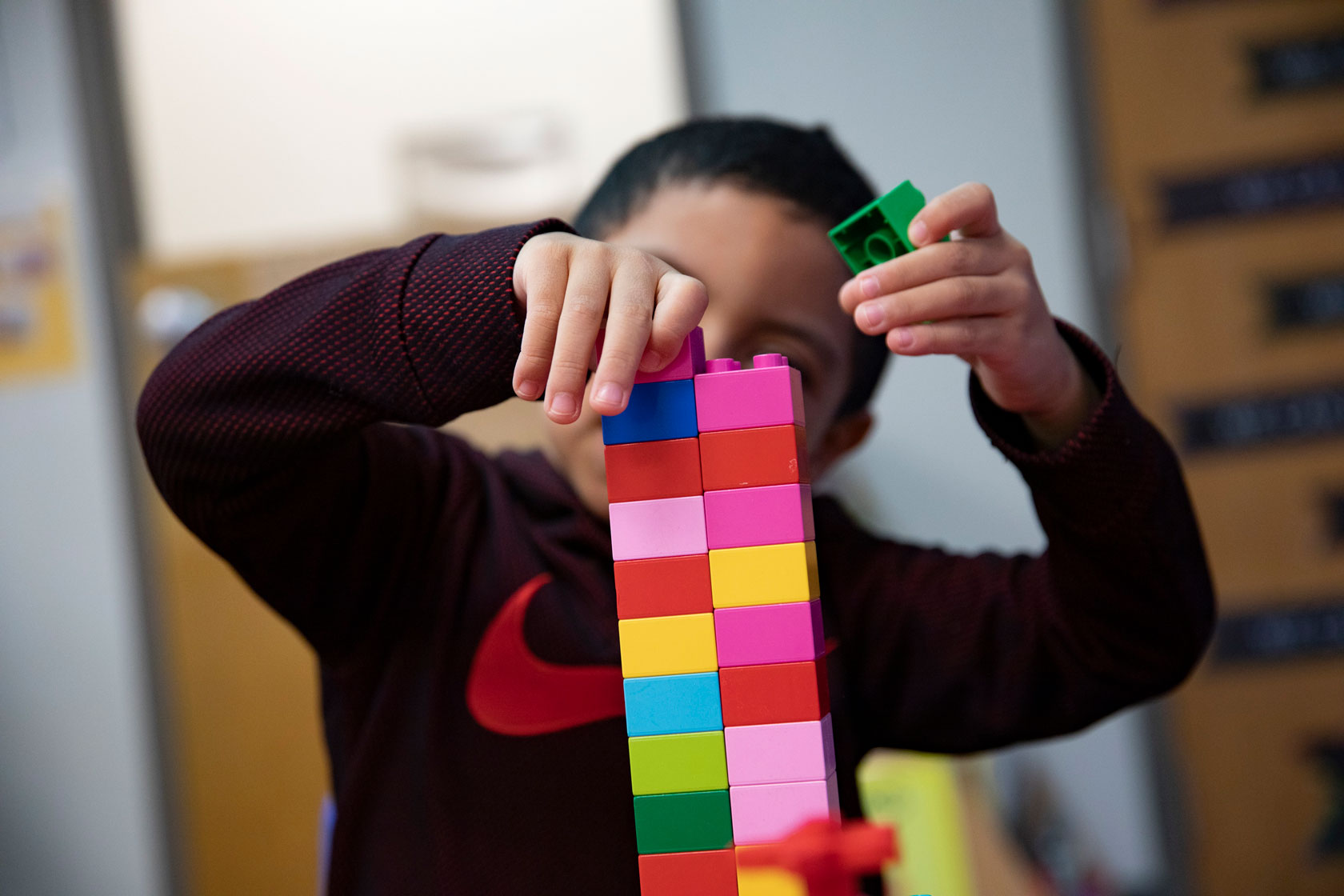 A child stacks duplo legos to make a tower in a Head Start classroom for children ages 3 to 5.