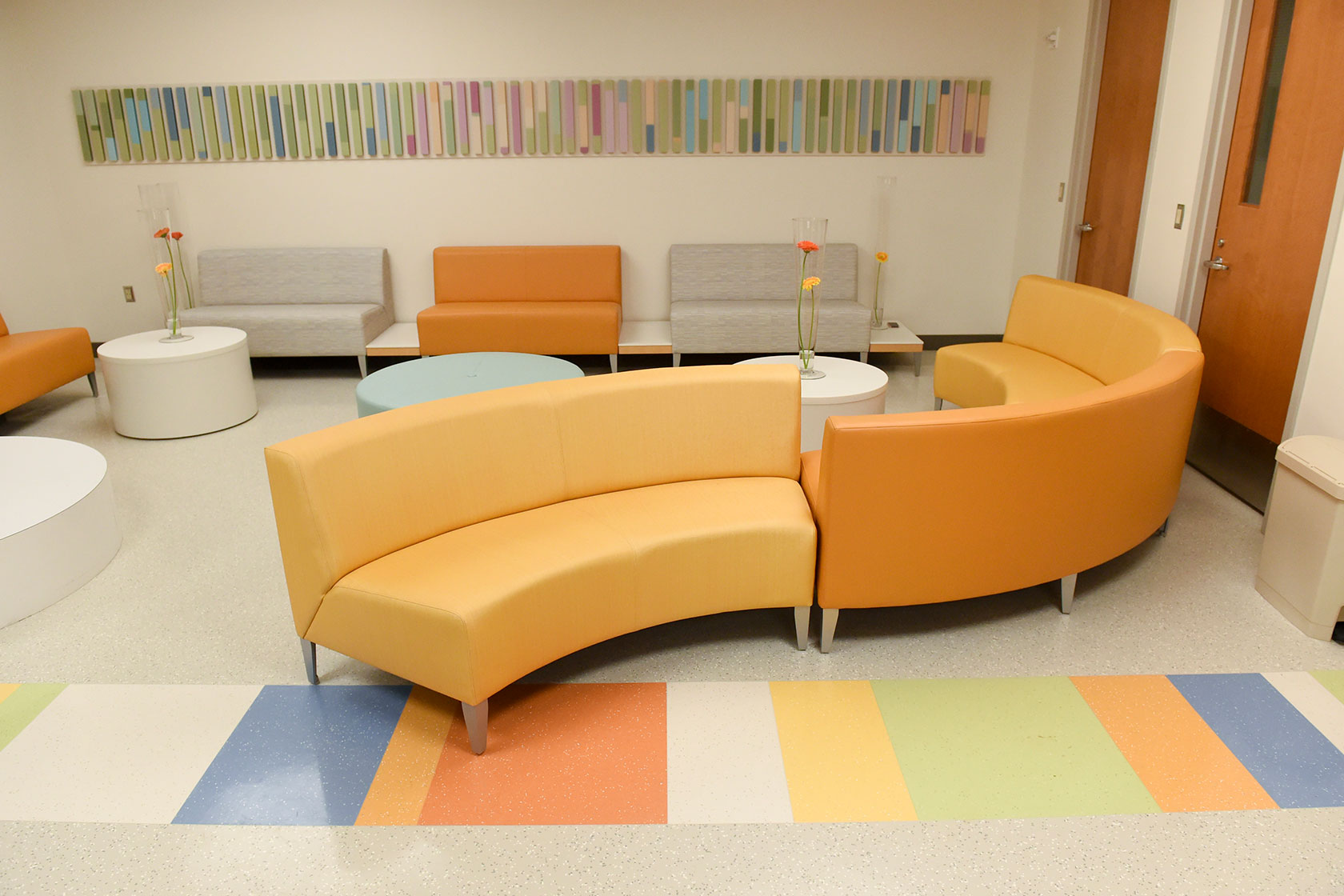 Photo shows a pastel-colored waiting room with orange couches sitting empty