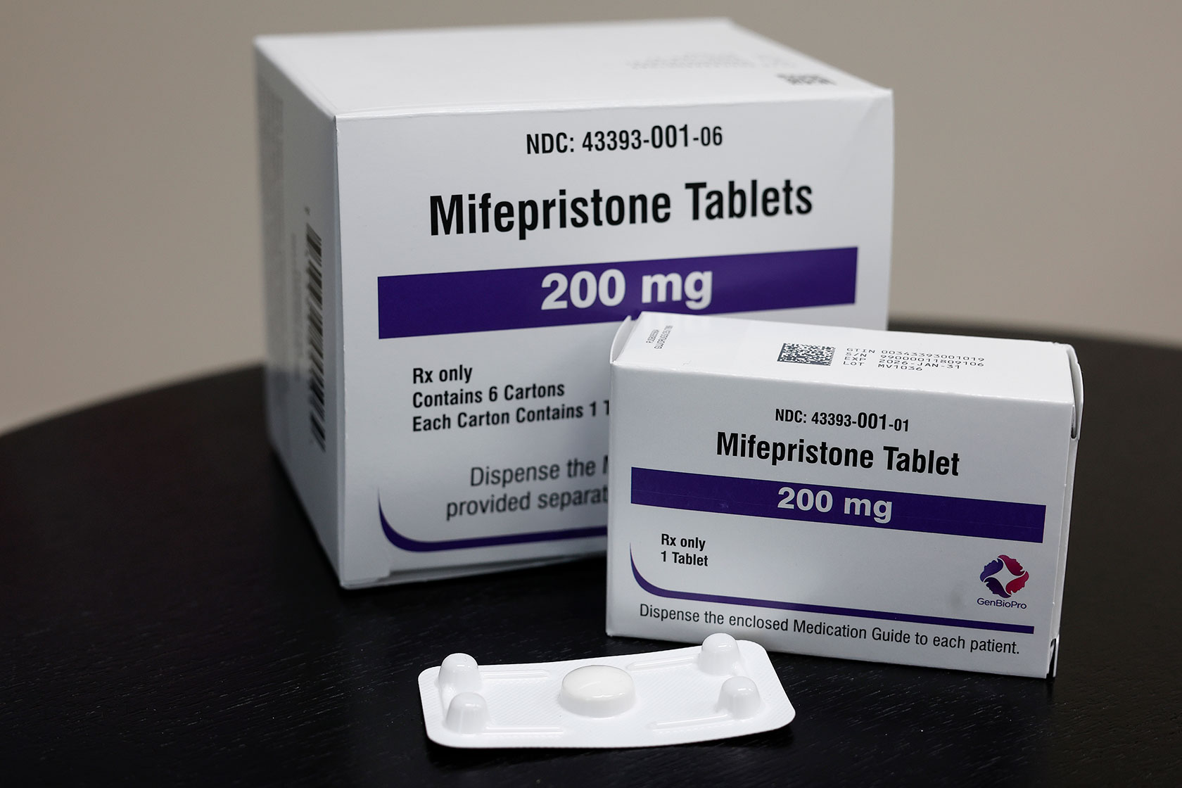 Photo shows two white boxes sitting on a black surface. Both boxes display information about the medication they contain, mifepristone.
