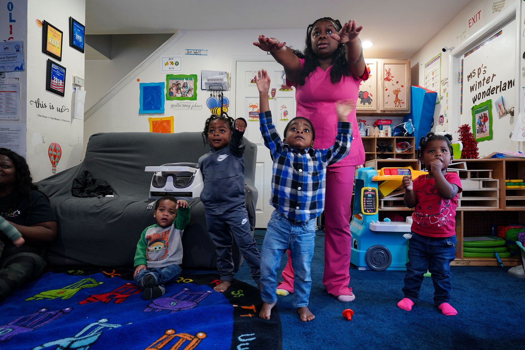 An early childhood educator exercises with toddlers.