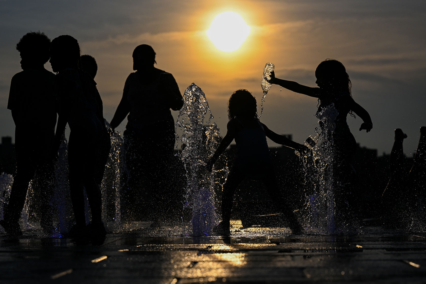 Young children cool off by playing in a fountain in Brooklyn, New York’s Domino Park.