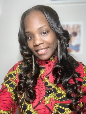 Shawana Moore smiles for a selfie, wearing a red patterned shirt