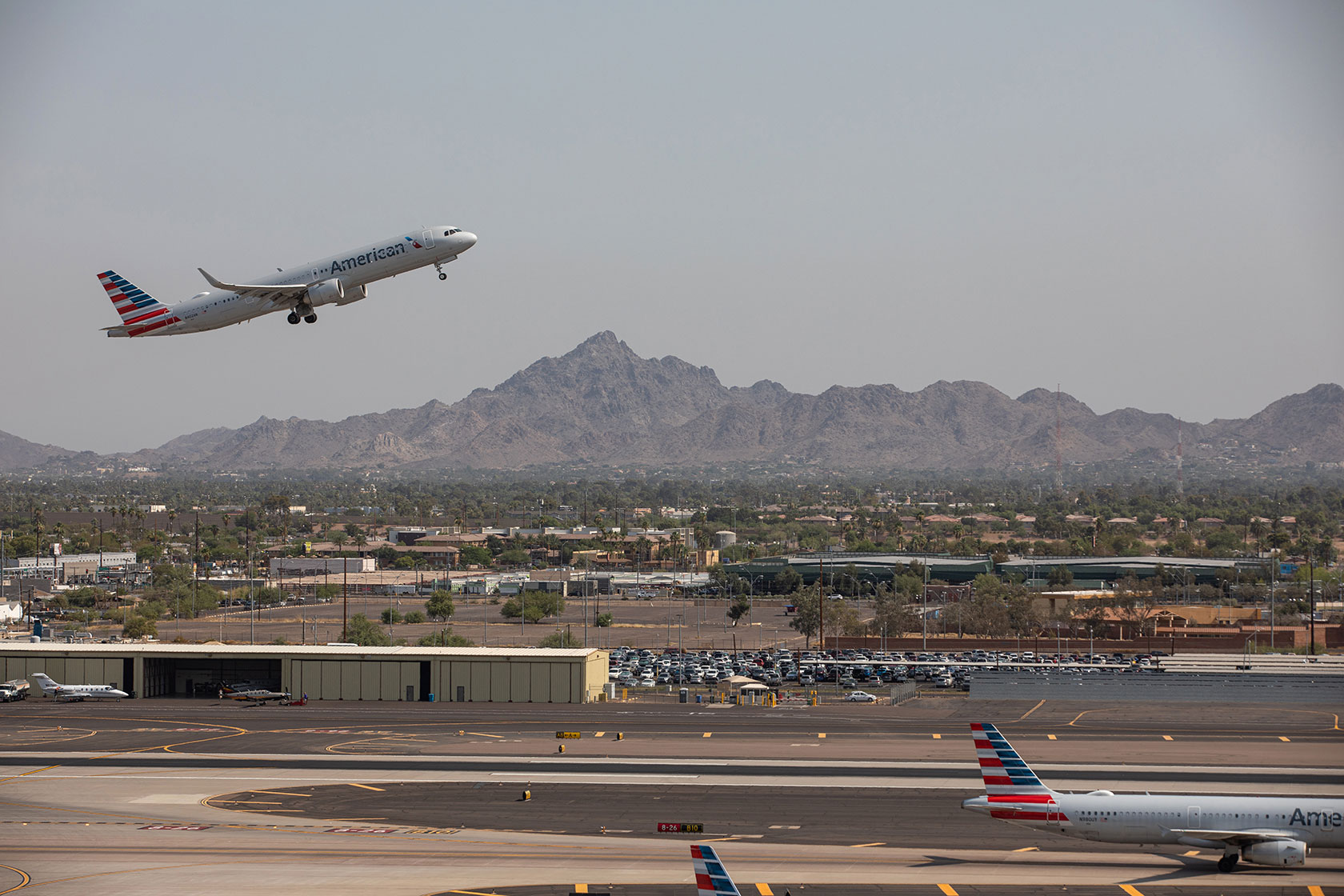 Photo shows an American Airlines plane taking off against a dry mountain background