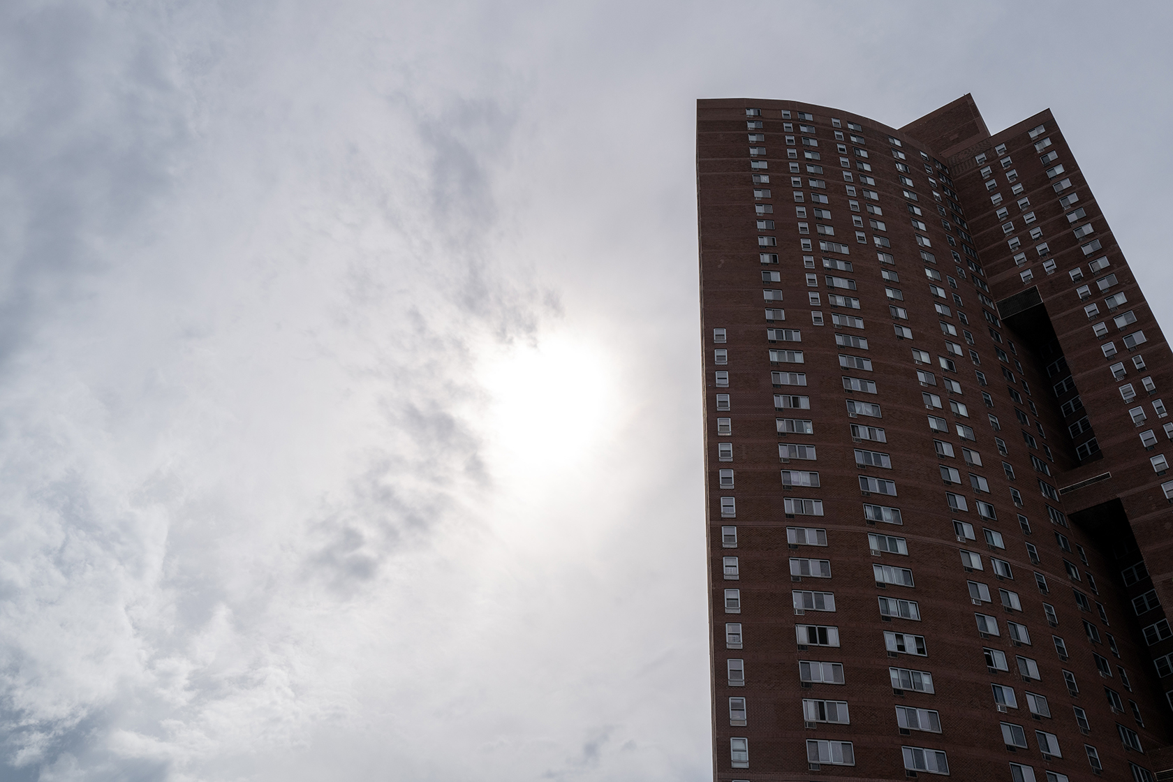 Sun coming through clouds behind apartment building