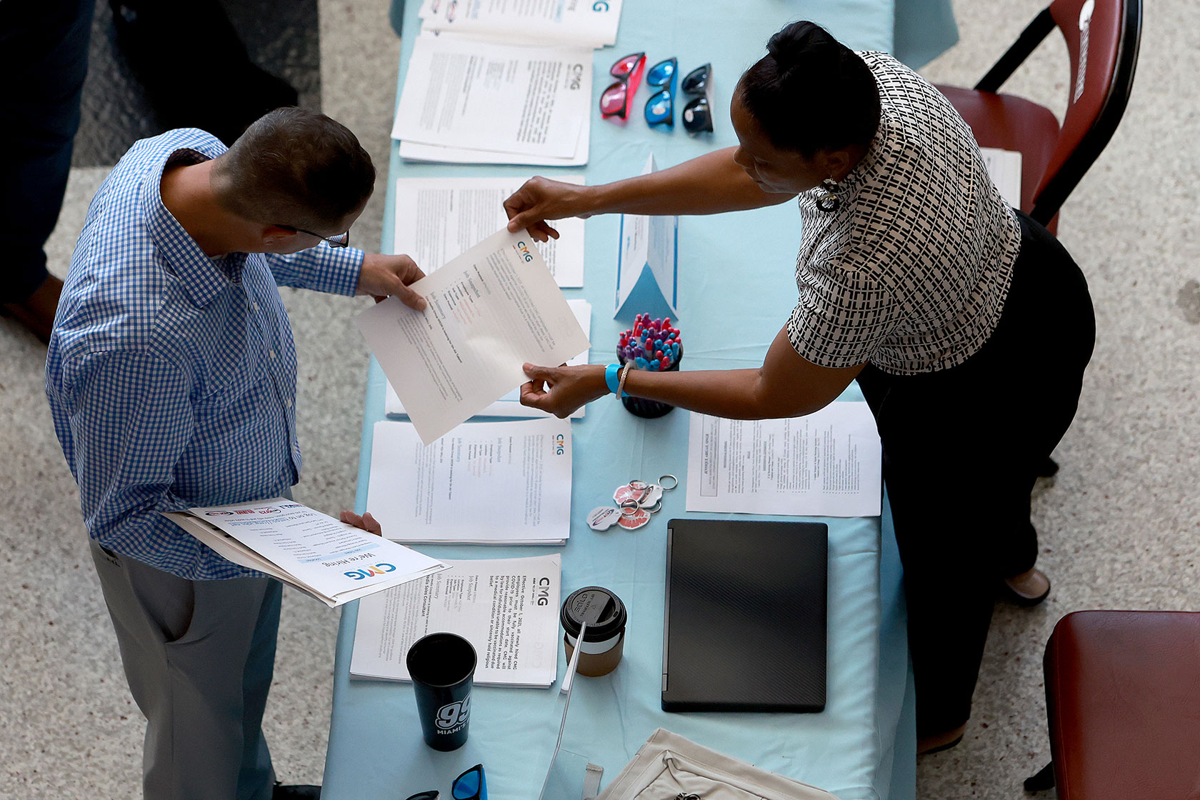 A recruiter helps people look for work during a job fair.