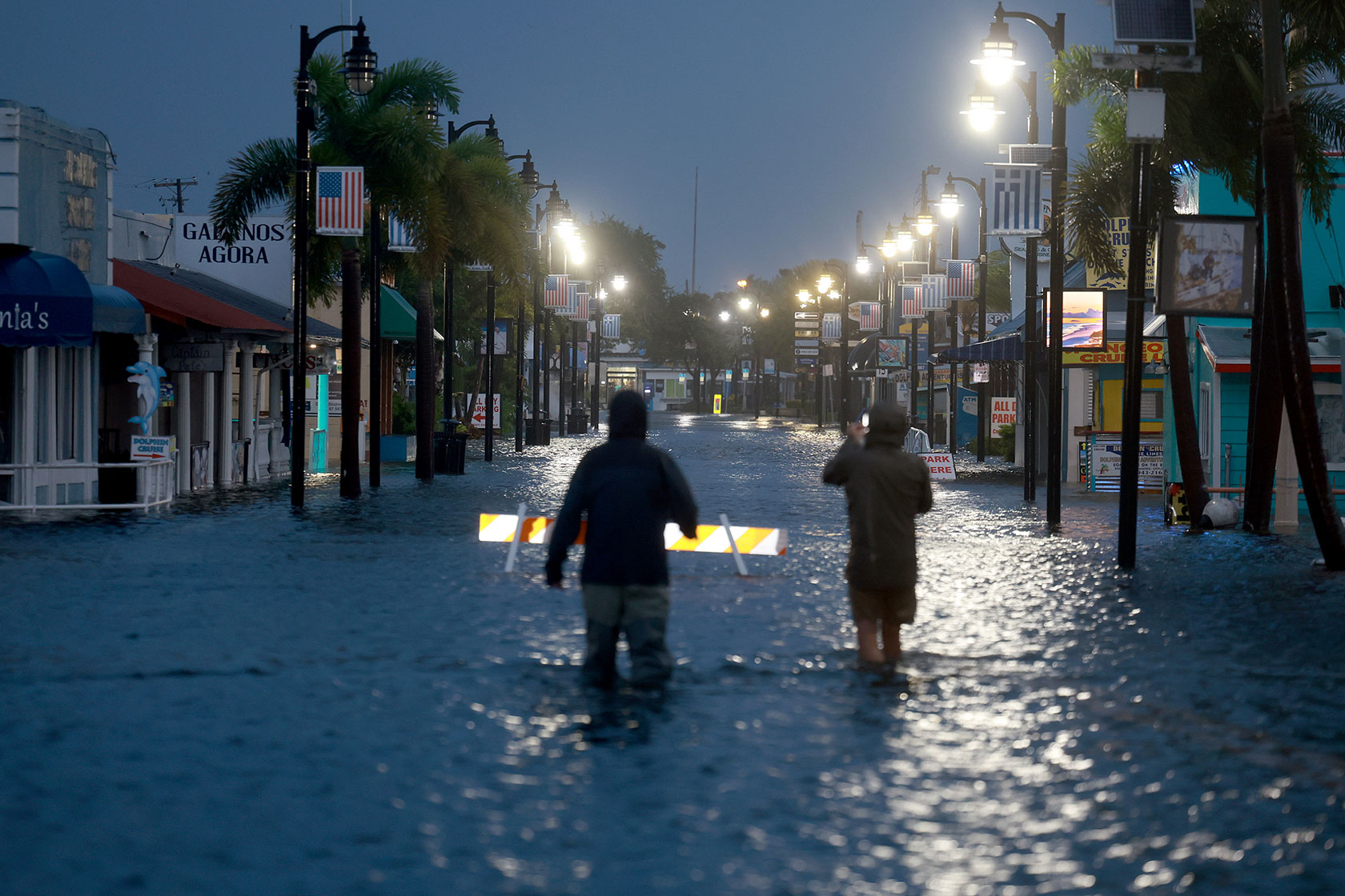 Reporters wade through flood waters in Tarpon Springs, Florida.