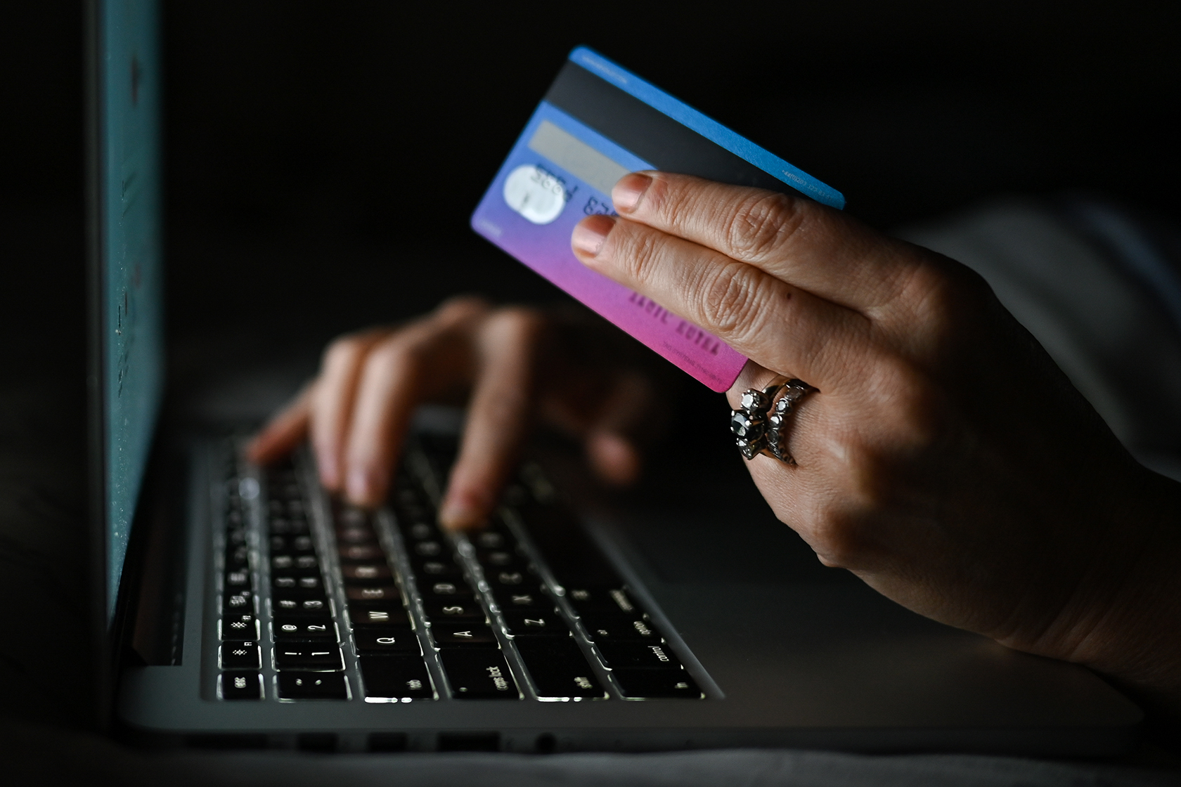 Close-up keyboard of computer and hand holding credit card