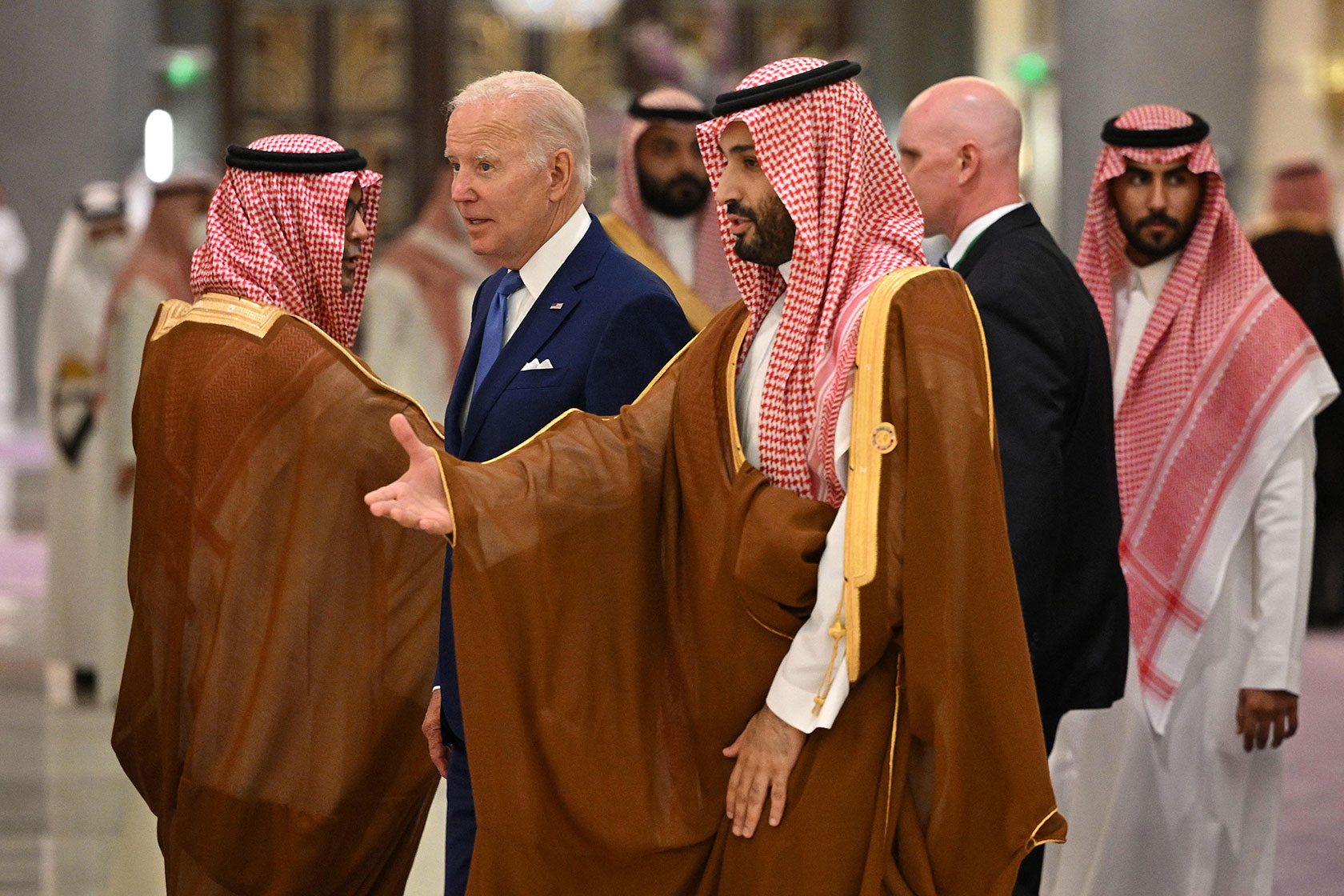 Photo shows Joe Biden and Mohammed bin Salman talking as they walk, passing by other Saudi officials