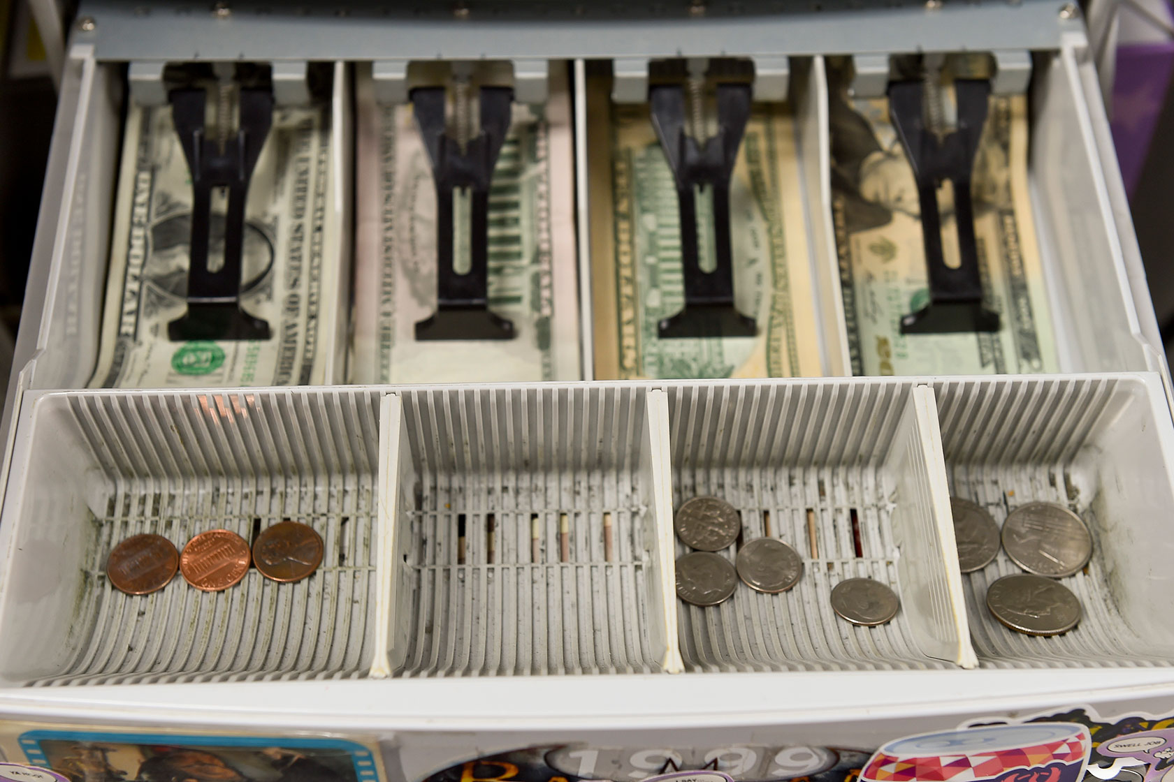 Photo shows an open change drawer with bills and coins