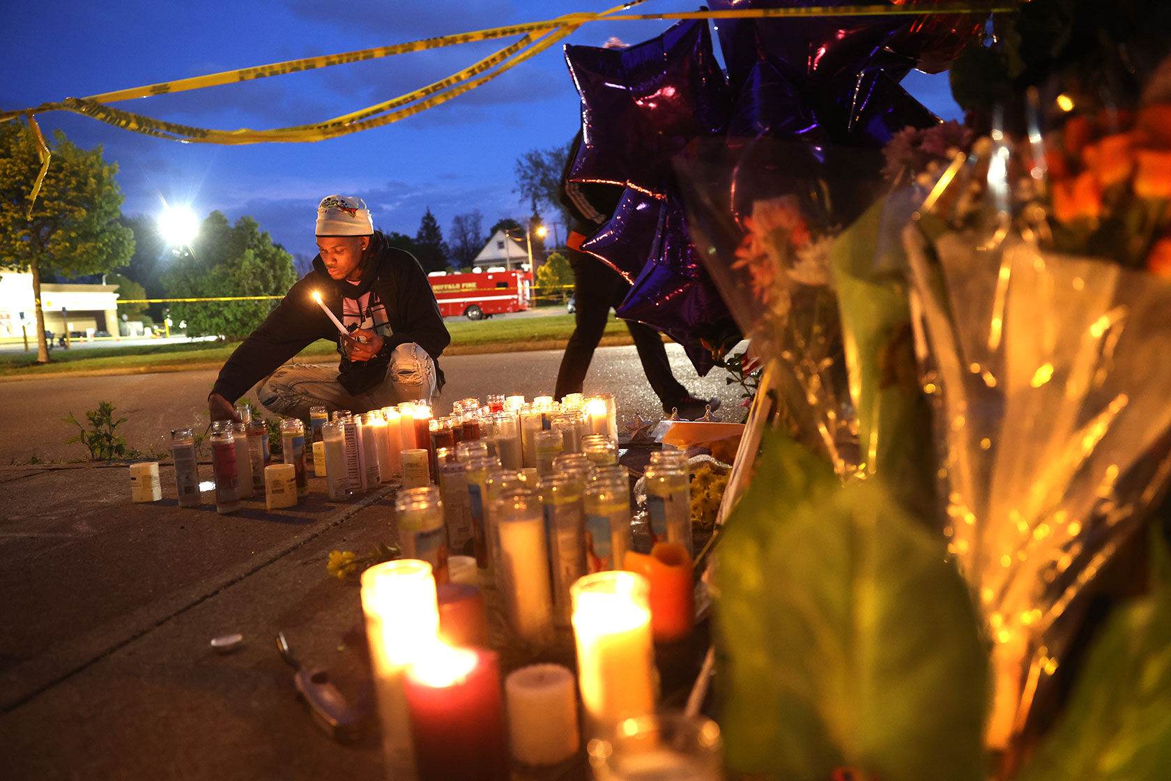 Photo shows a young man lighting a candle in the late evening
