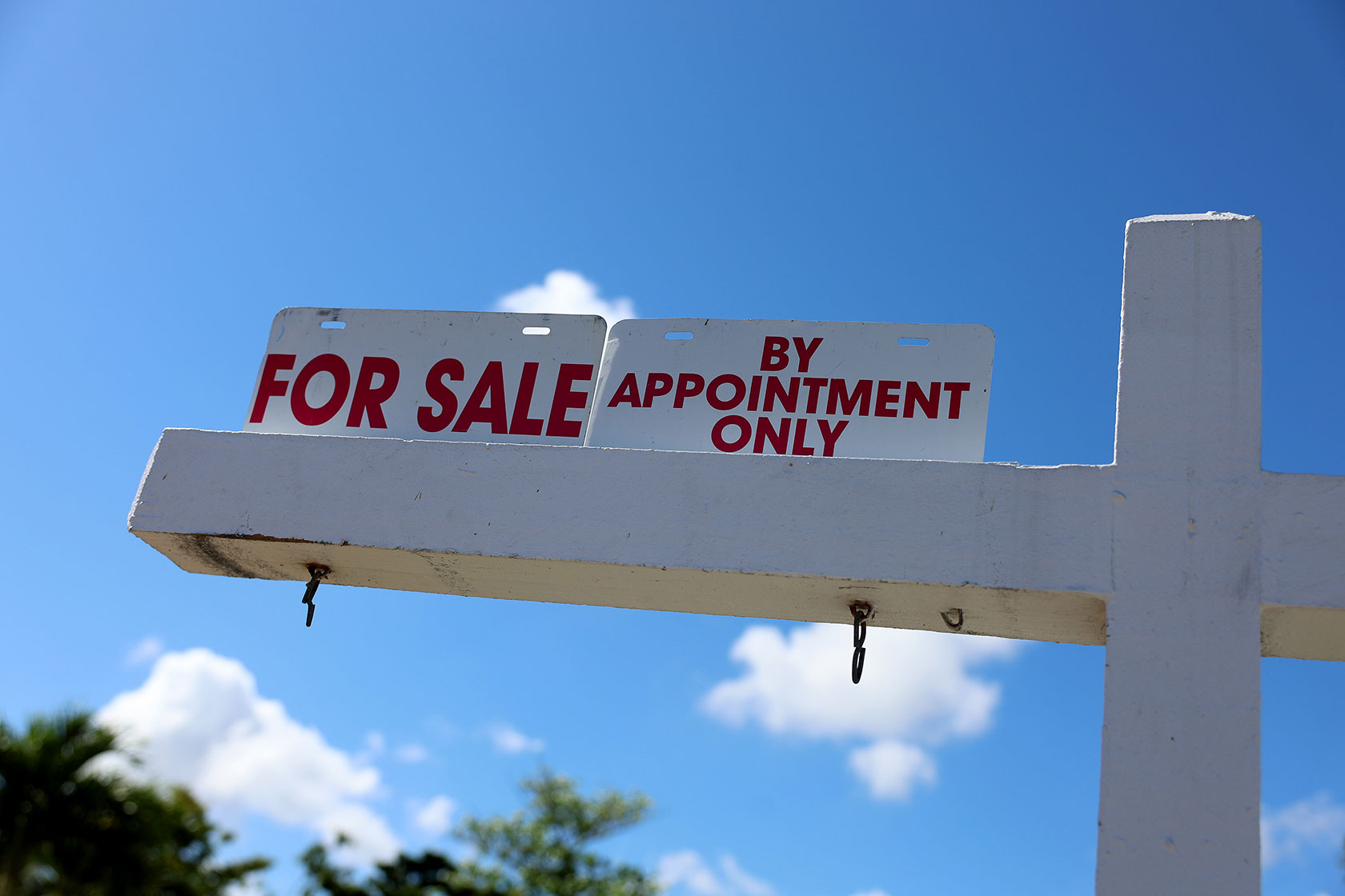 Photo shows a white signpost displaying a sign that says 