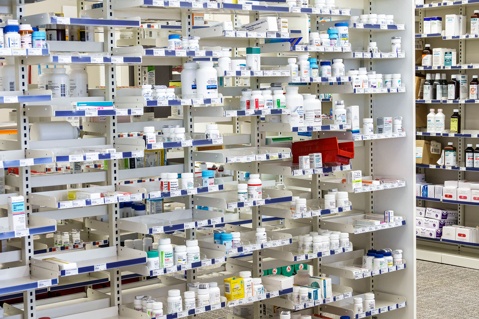 Photo shows pharmacy shelves stocked with bottles and boxes of prescription drugs.