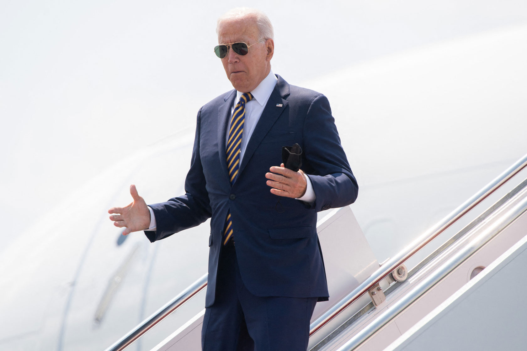 Photo shows Joe Biden wearing a suit as he steps exists an airplane on a sunny day