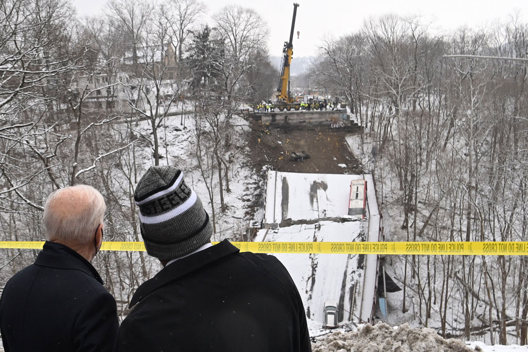 Photo shows Joe Biden and Ed Gainey facing the snowy construction site of the Fern Hollow Bridge.