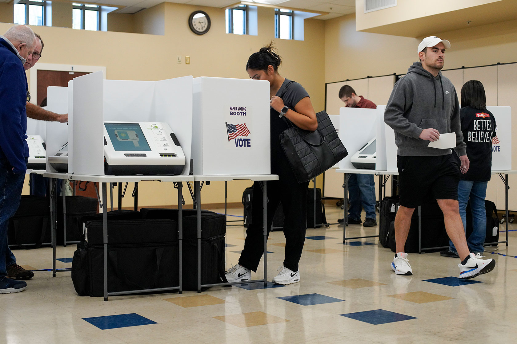 Photo shows several people at polling stations filling out their ballots in a well-lit room