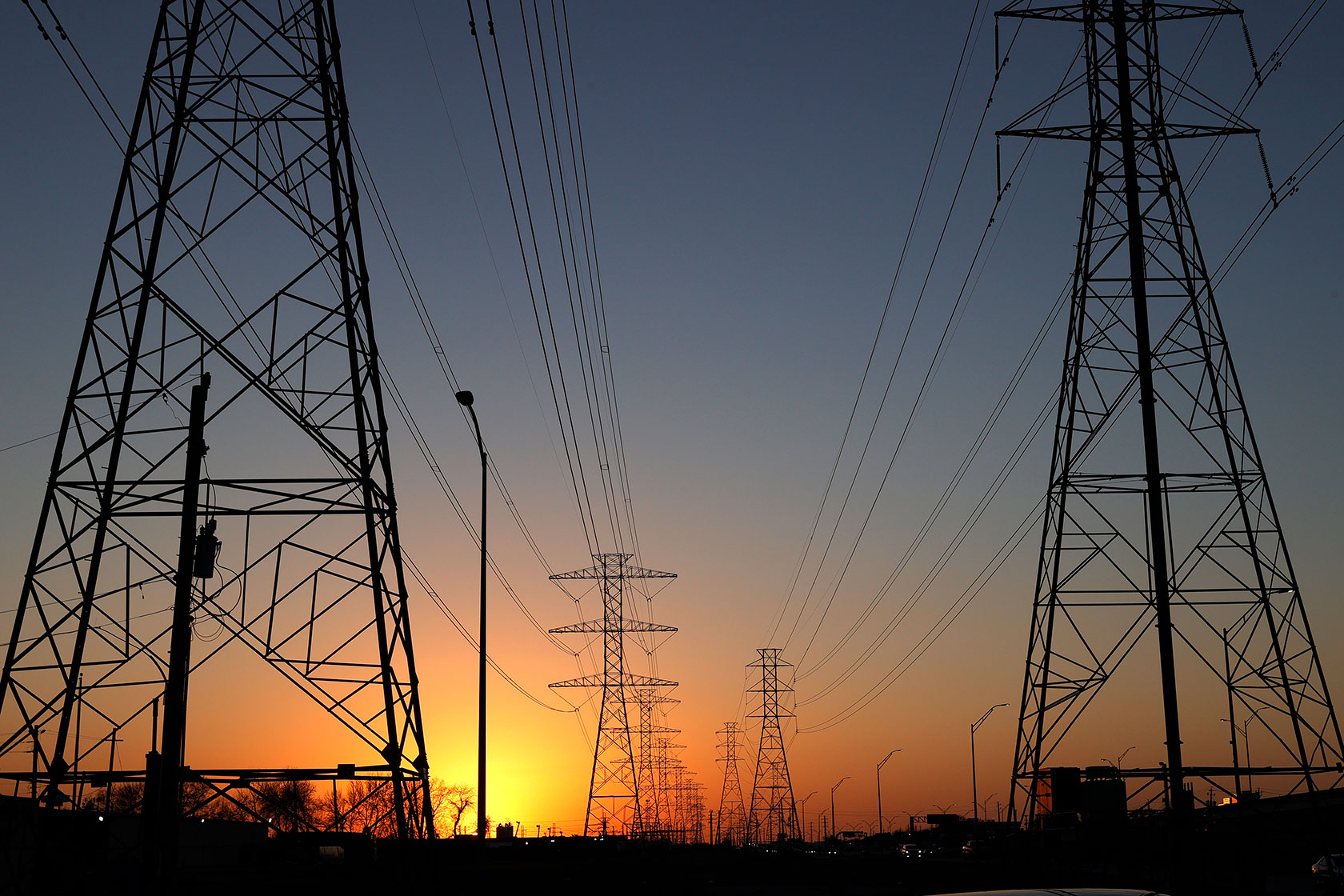 The sun sets behind high-voltage transmission towers in Houston.