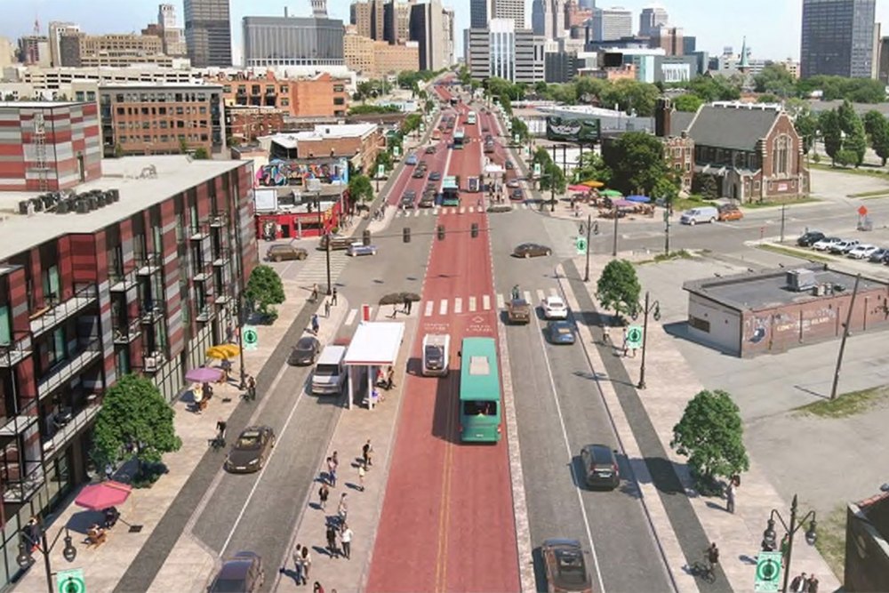 Image shows a street with buses, cars, bikes, and pedestrians in front of a city skyline.