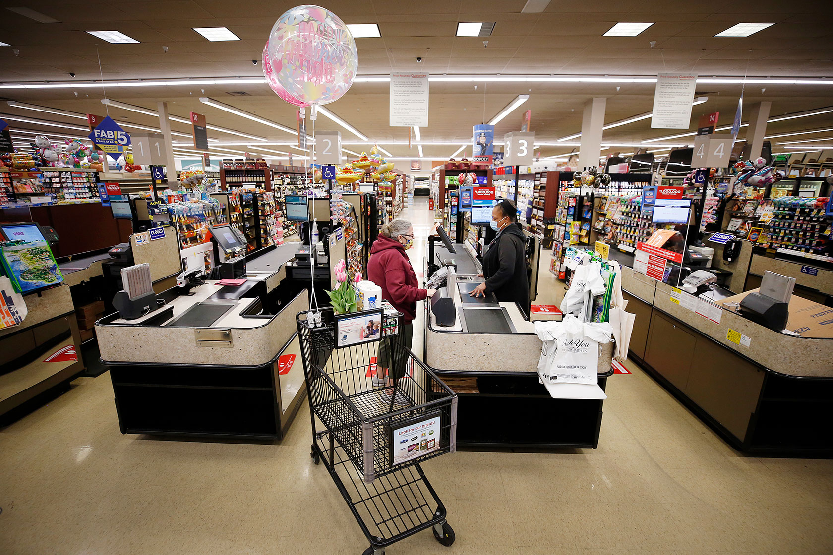 Photo shows a woman ringing up another woman in a grocery store