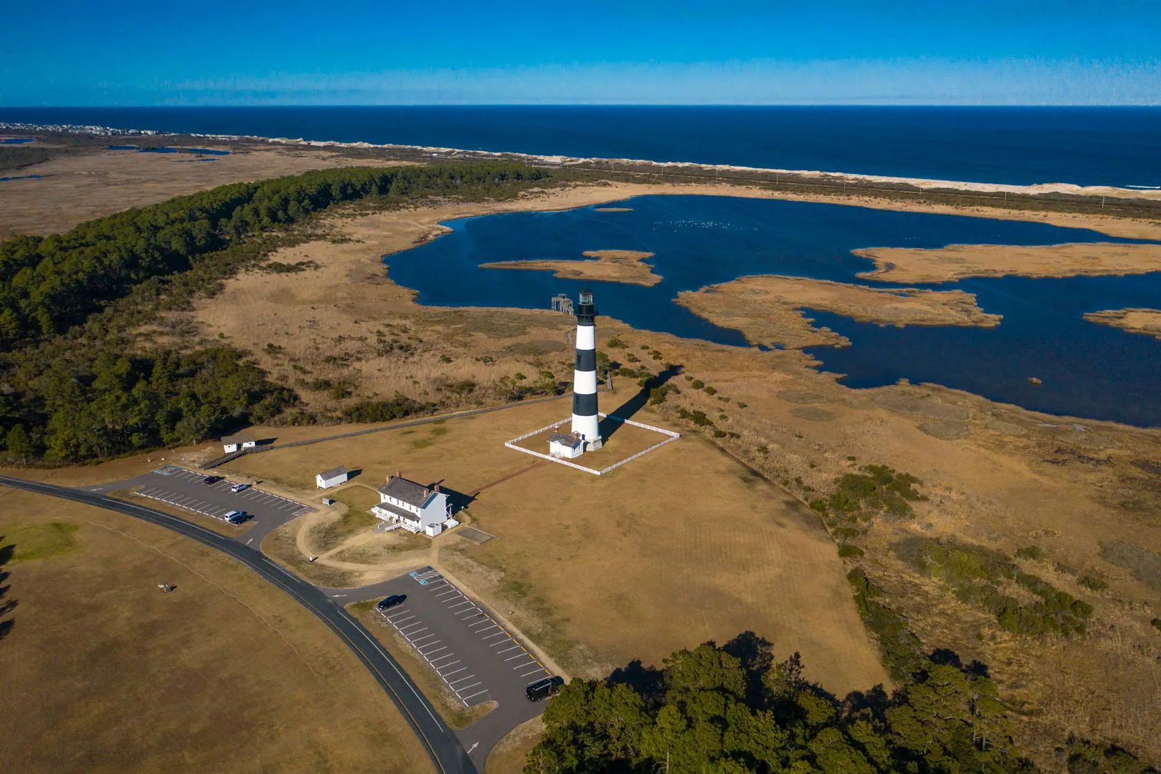A lighthouse station is seen from above with tidal waters in the background.