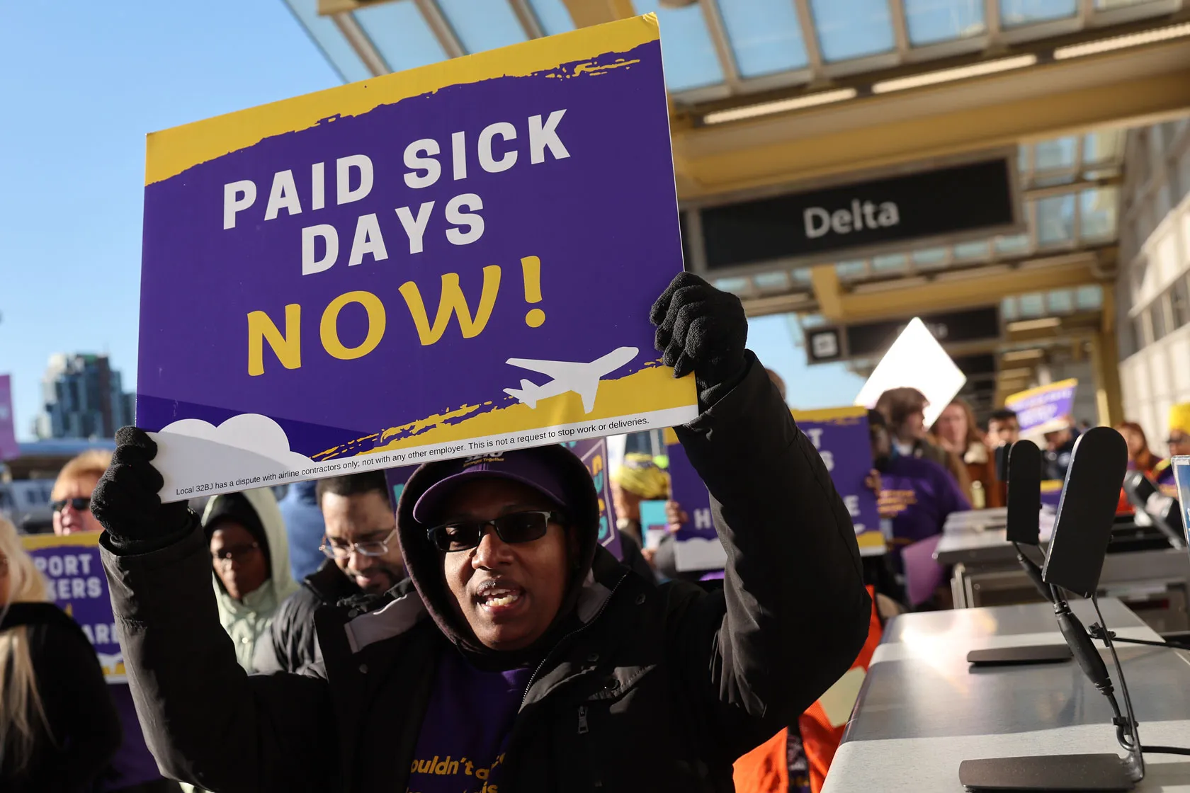 Workers hold signs in favor of paid sick days.