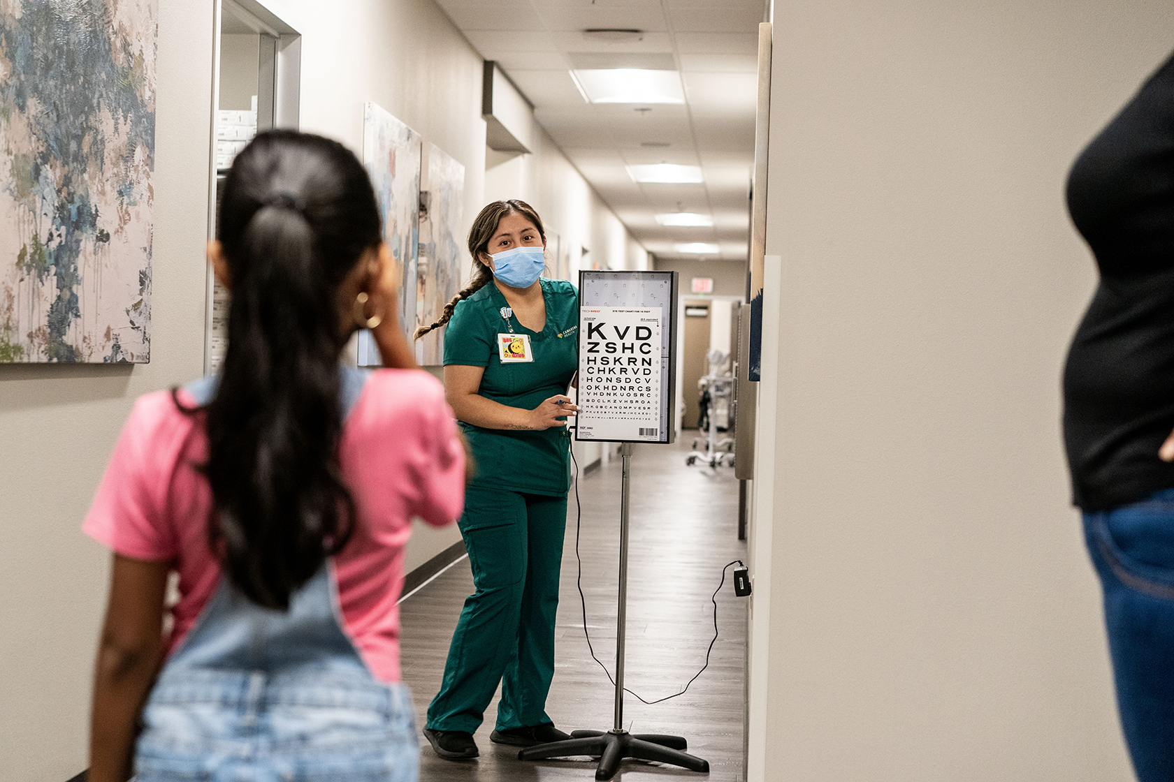 Child with back to camera as health care worker does vision test