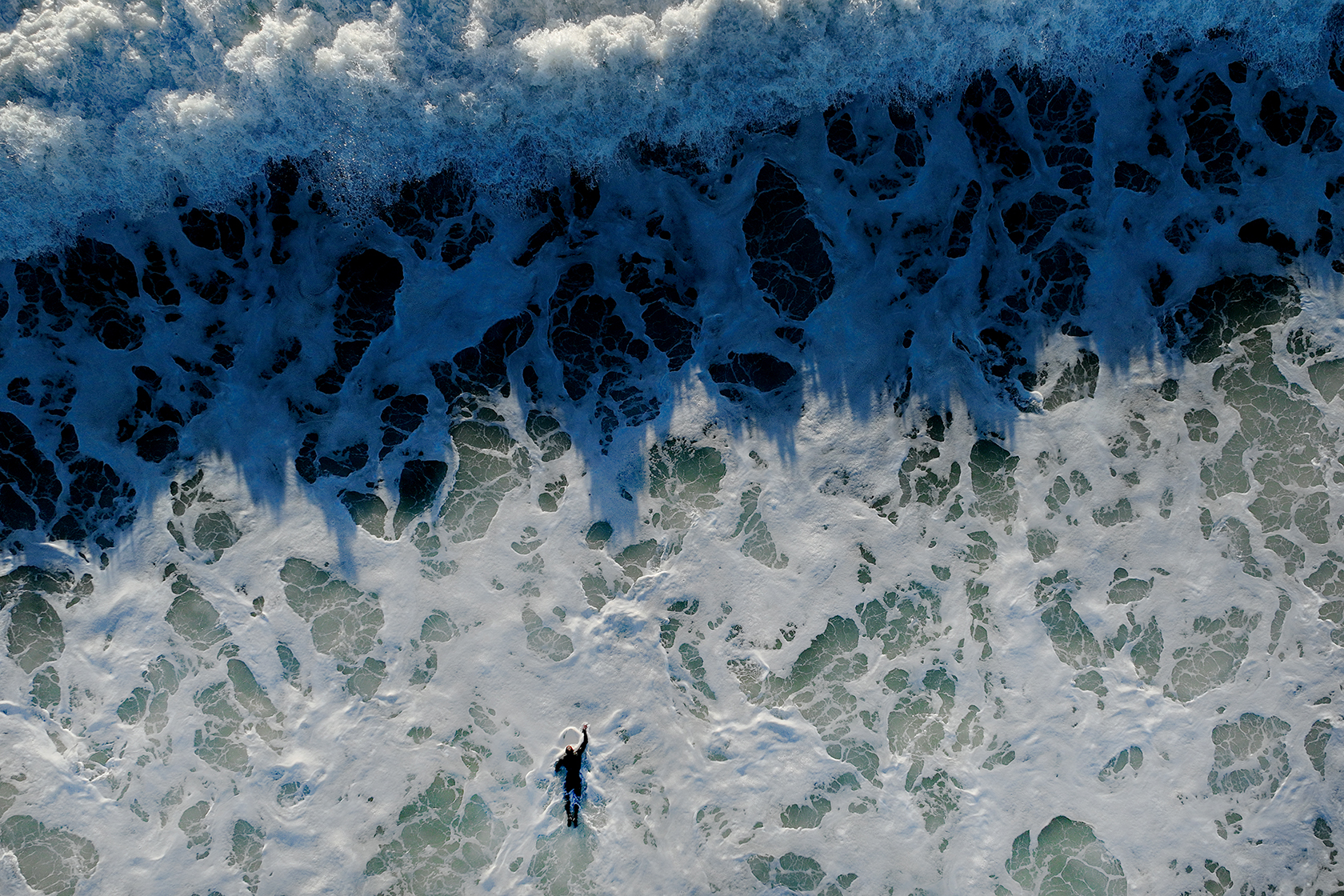 Overhead view of surfer paddling out to a wave