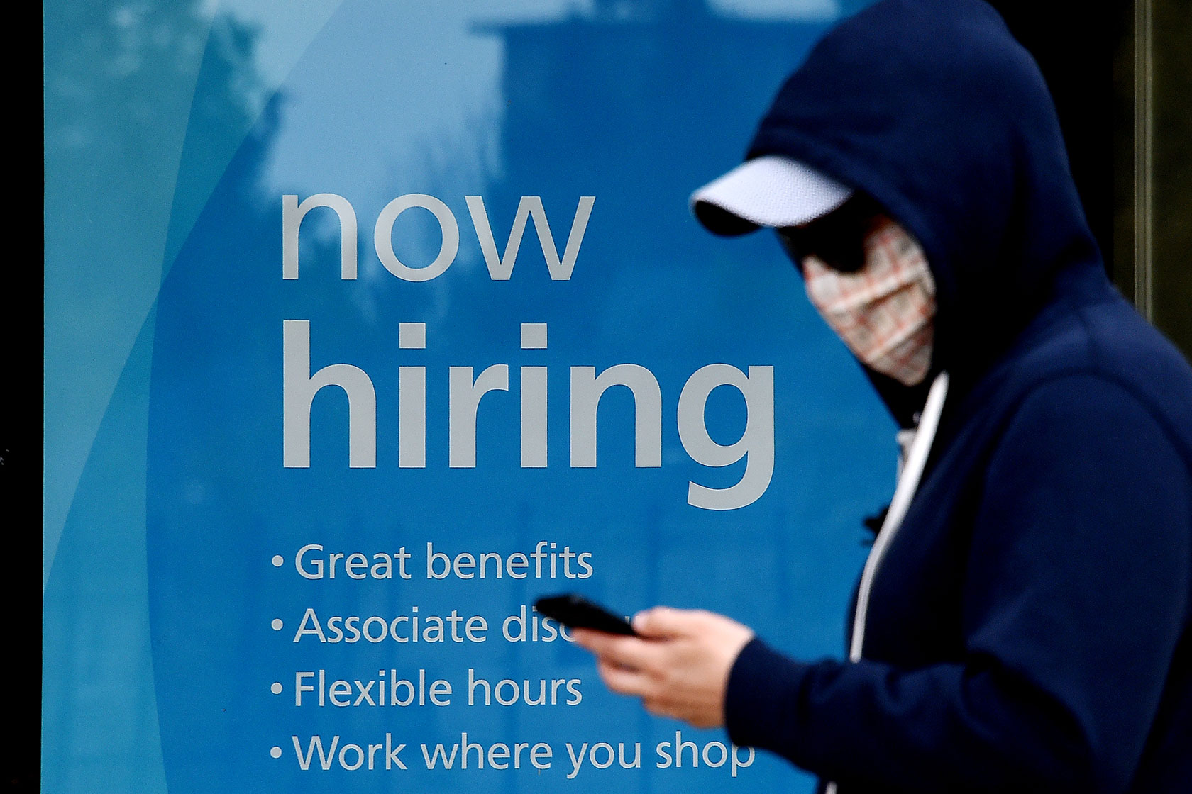 A man walks past a store window with a sign reading 