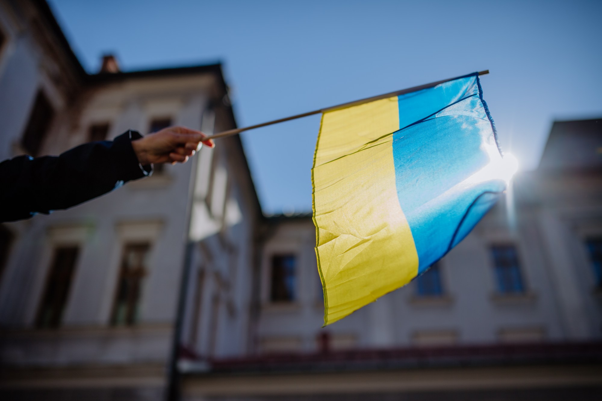 Arm stretched out holding a Ukrainian flag.