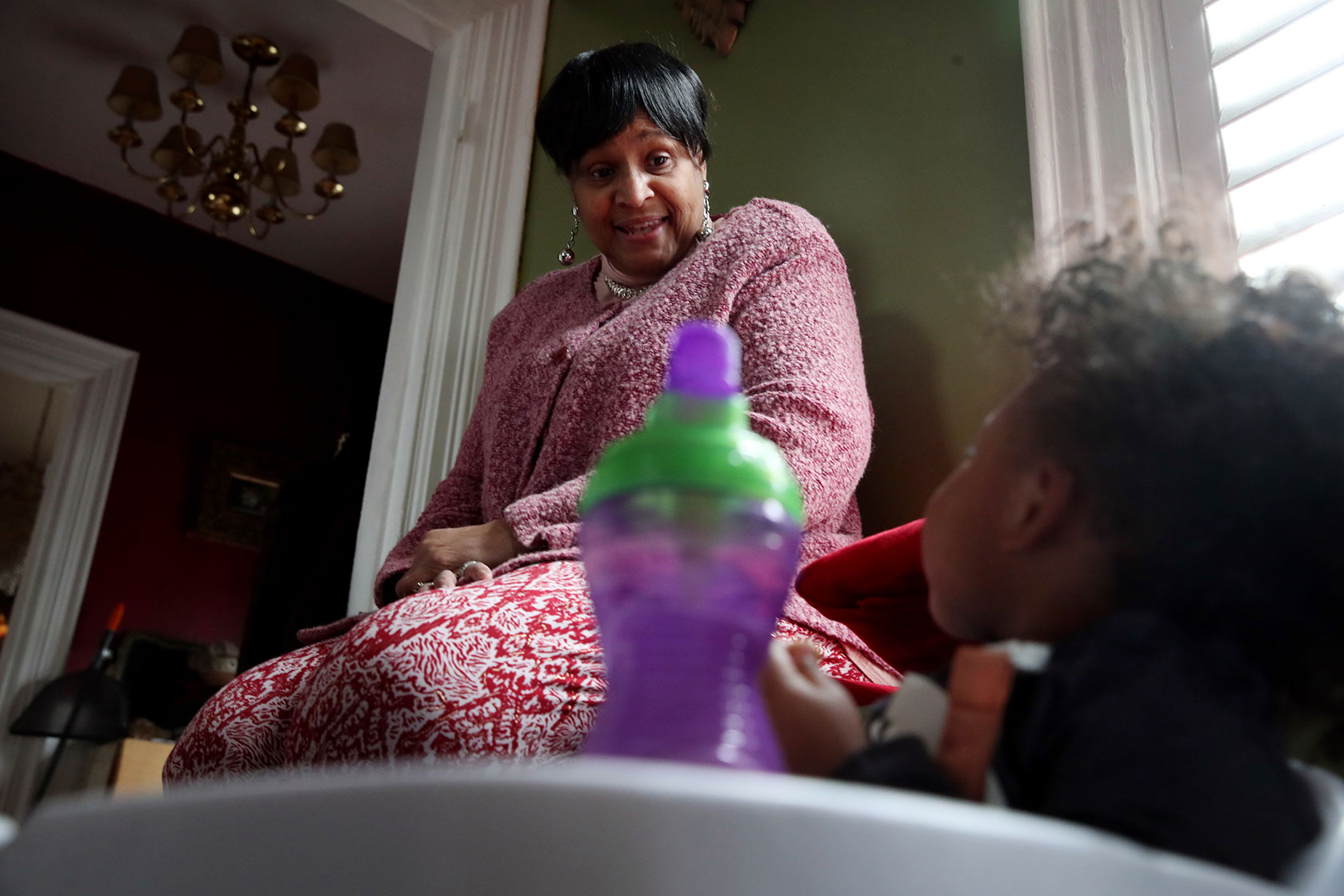 Child care worker looking at baby in high chair