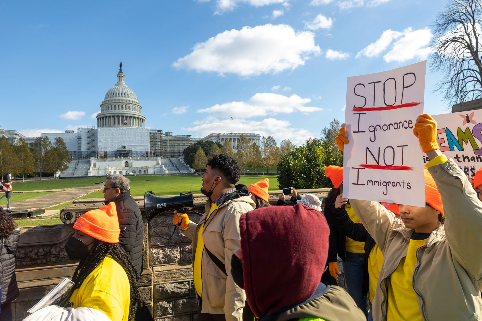 A group of people holding signs is seen with the U.S. Capitol building in the background.