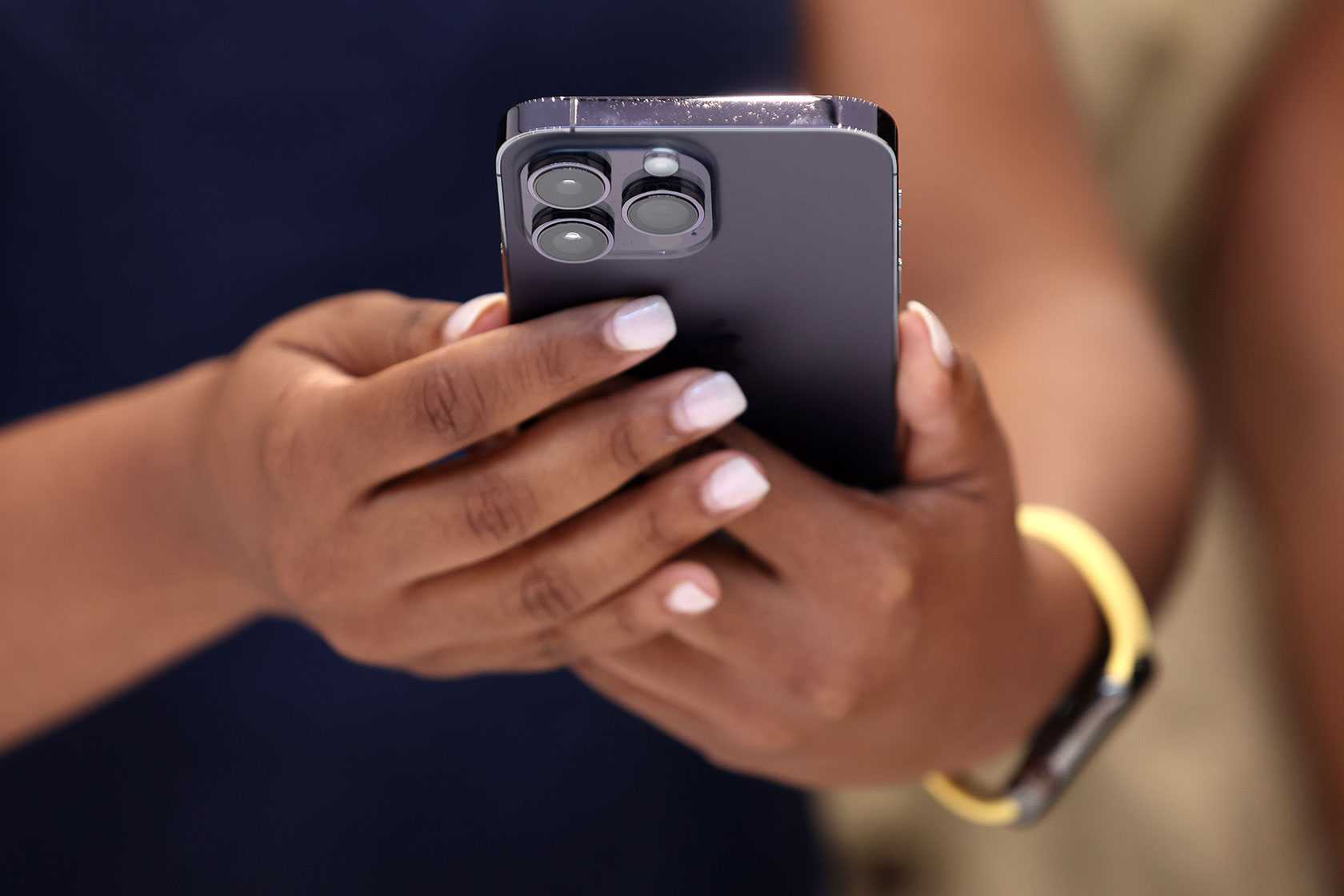 Photo shows a closeup of a person's hands cradling a dark gray iphone