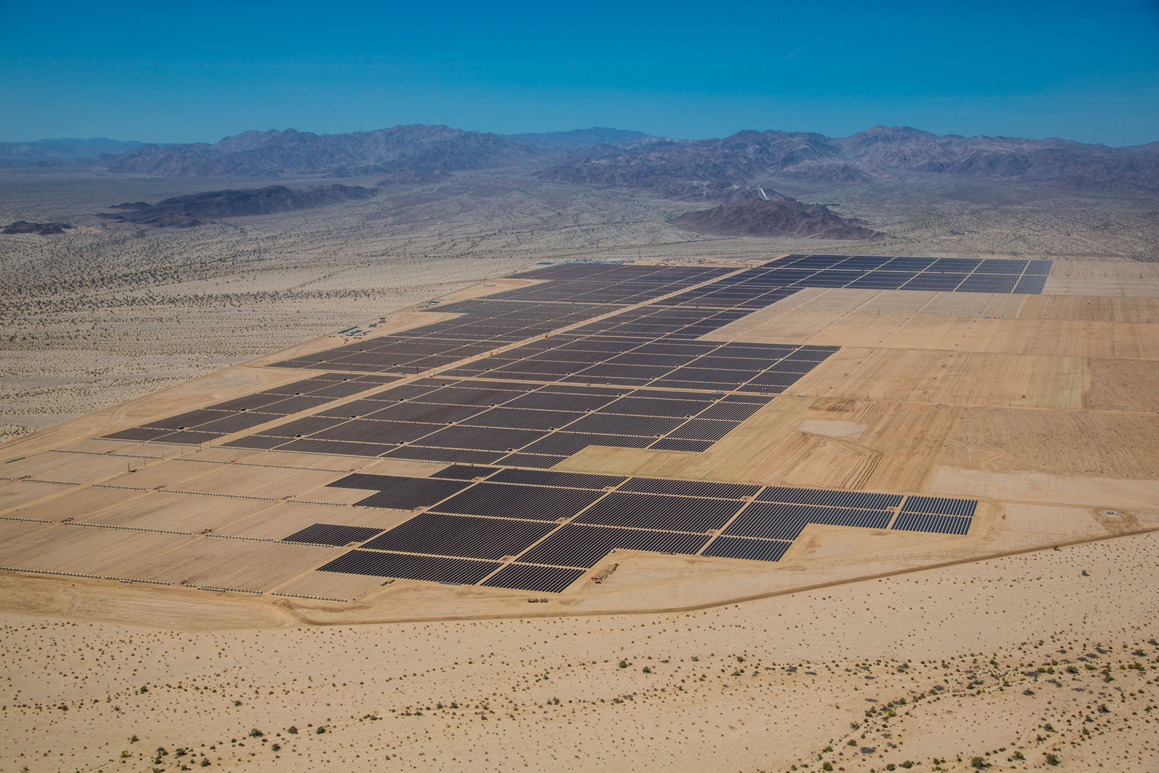 A field of solar panels is seen in the middle of the desert.