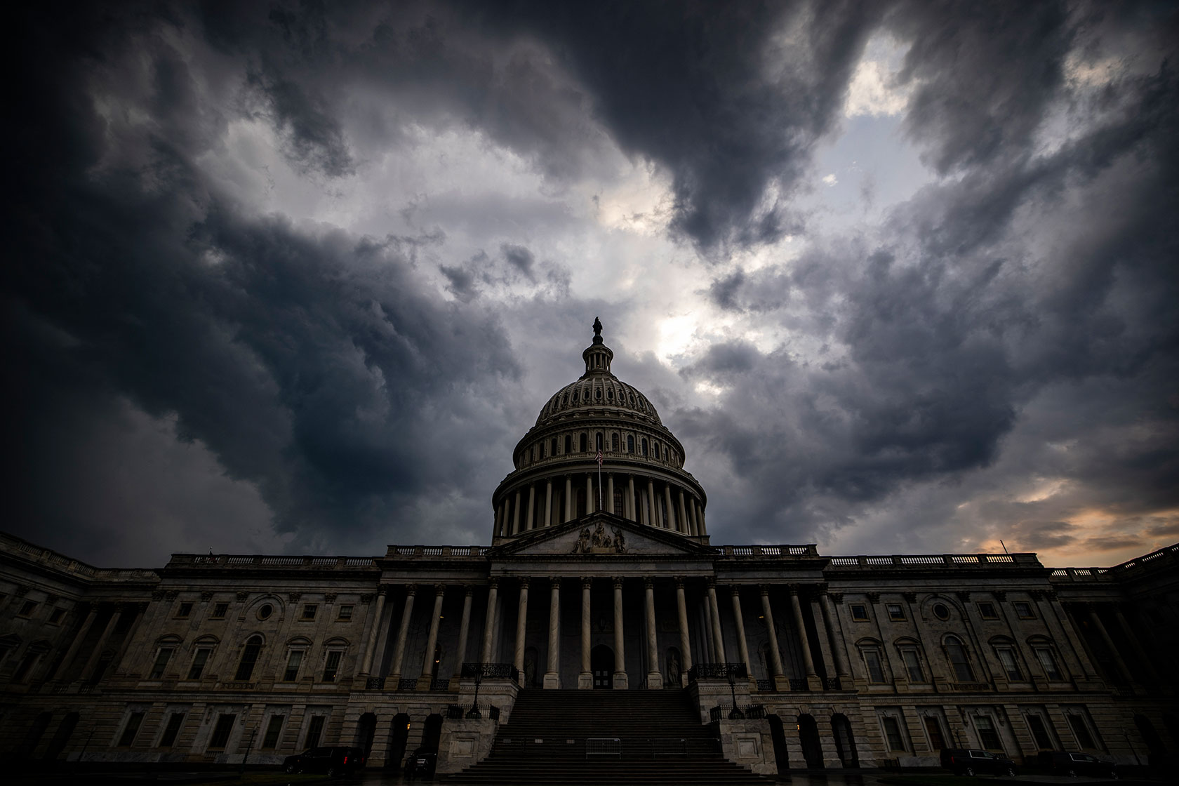 Photo shows the Capitol building against a background of dark gray storm clouds