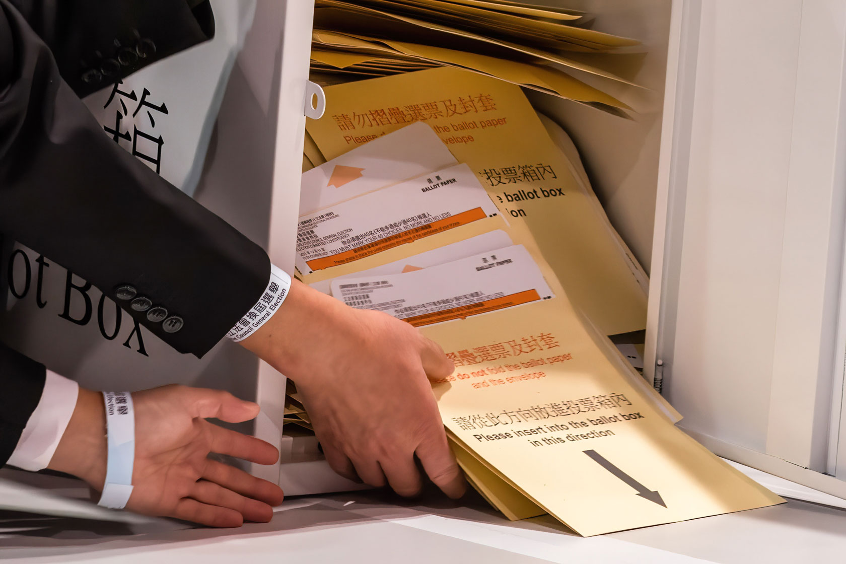 A box of ballots is seen being poured out onto a table.