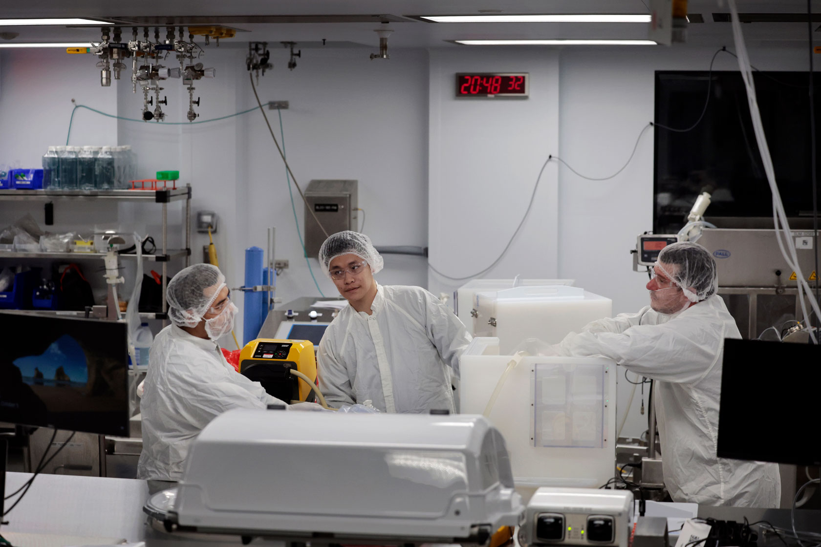 Three employees gather around a bioreactor.