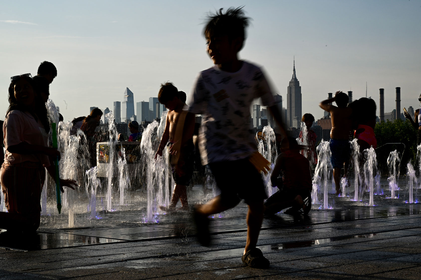 Children cool off by playing in a fountain in Brooklyn’s Domino Park, New York, during a heat wave.