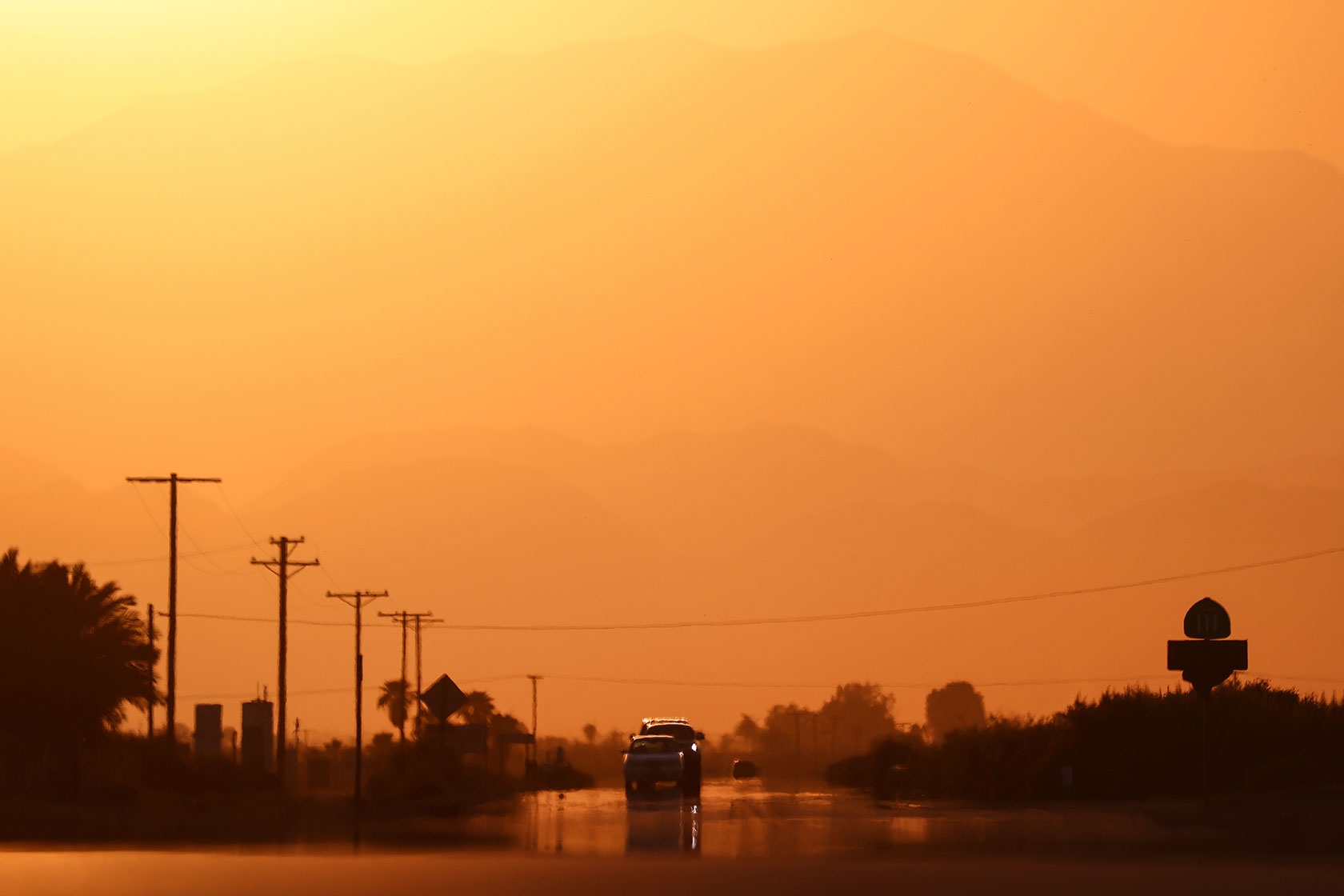 Vehicles are viewed above a ‘highway mirage’ caused by a thin layer of hot air above the roadway.