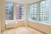 The corner of an empty apartment with windows that look onto office buildings in Lower Manhattan is seen.
