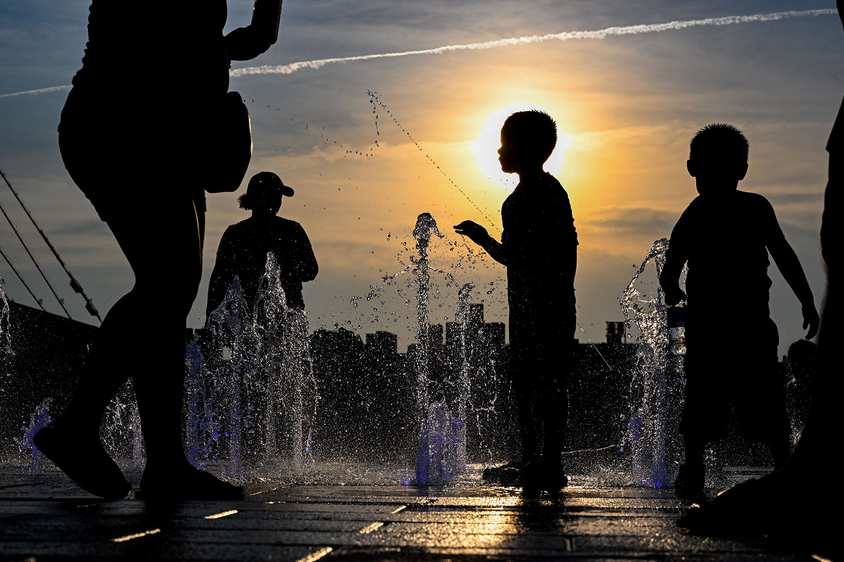 The sun sets in New York City as children cool off.