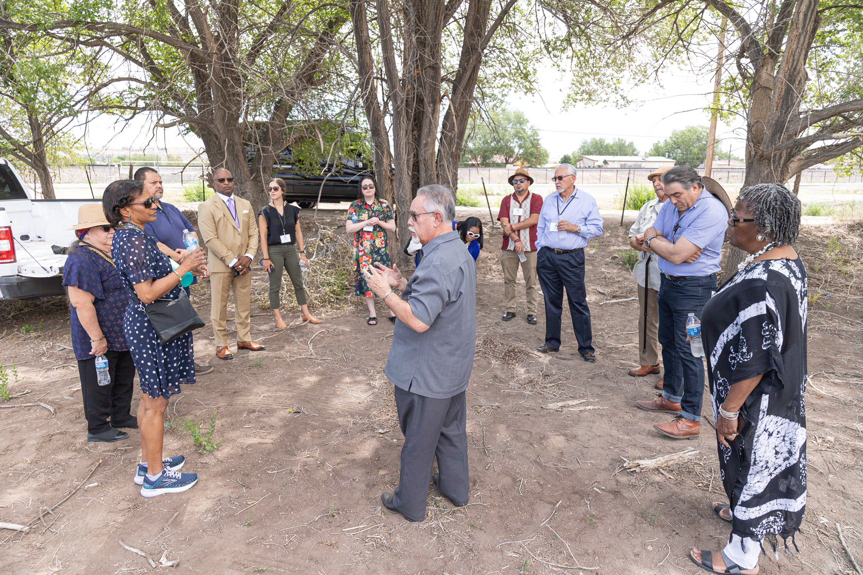 A group of environmental justice activists is seen in front of some trees and cars.